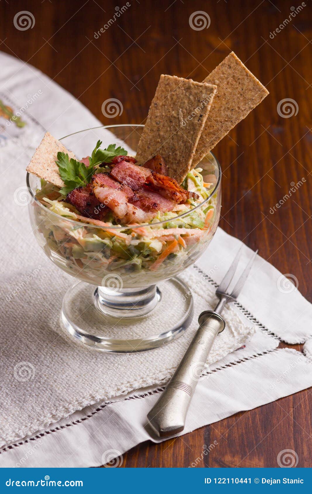 vitamin salad made of grated carrot and cabbage in white dip, covered with baked, crispy bacon and crunchy thins with flax seed.