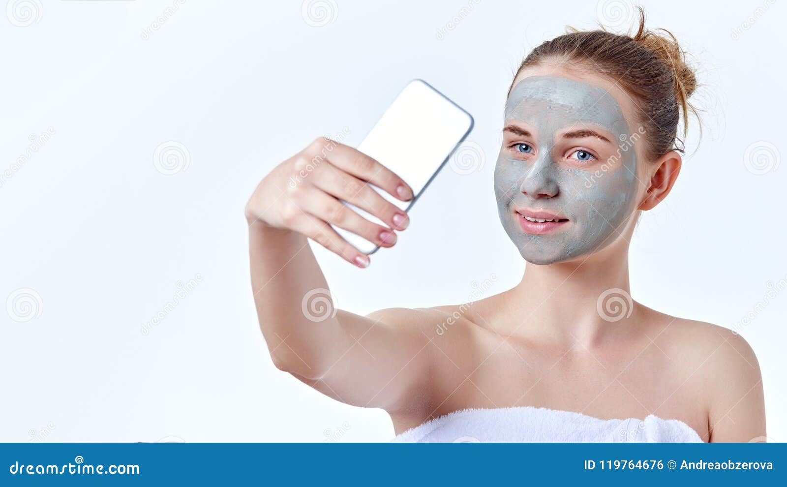 vlogging concept. young redhead teenage girl with dried face mask on her face using her smart phone to make video for her vlog.