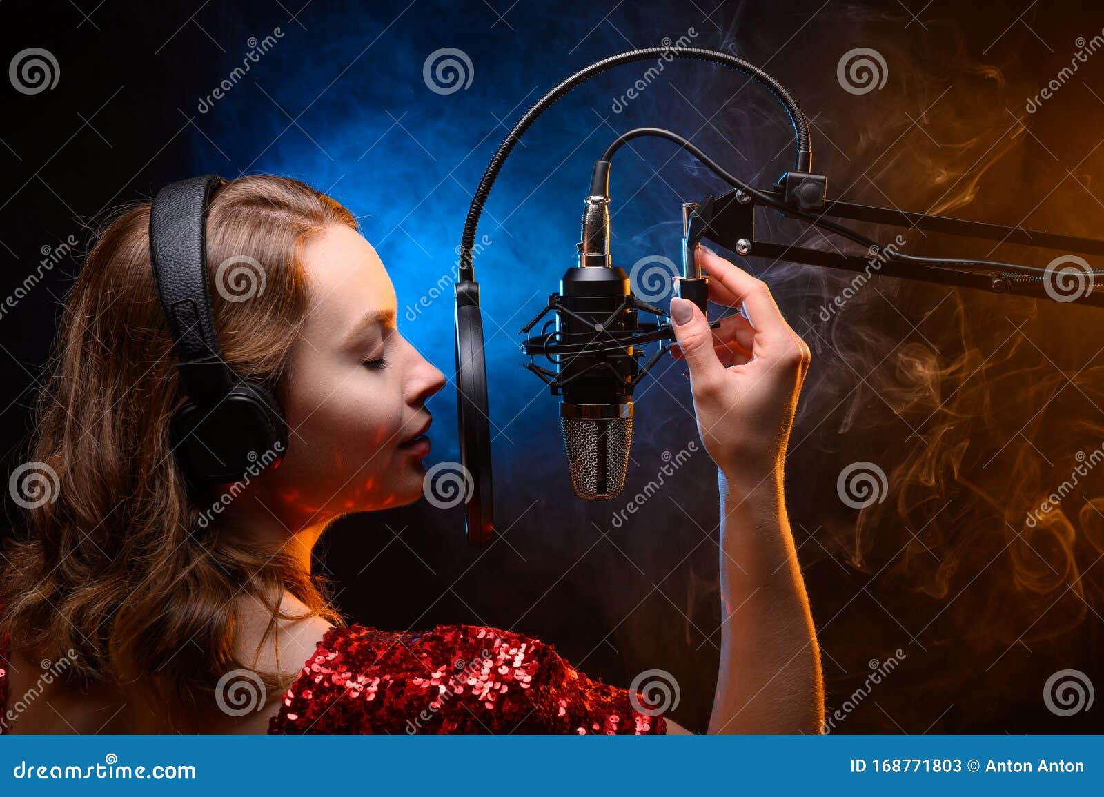 vocalist singing in the studio. school and vocals. against the backdrop of blue and orange smoke