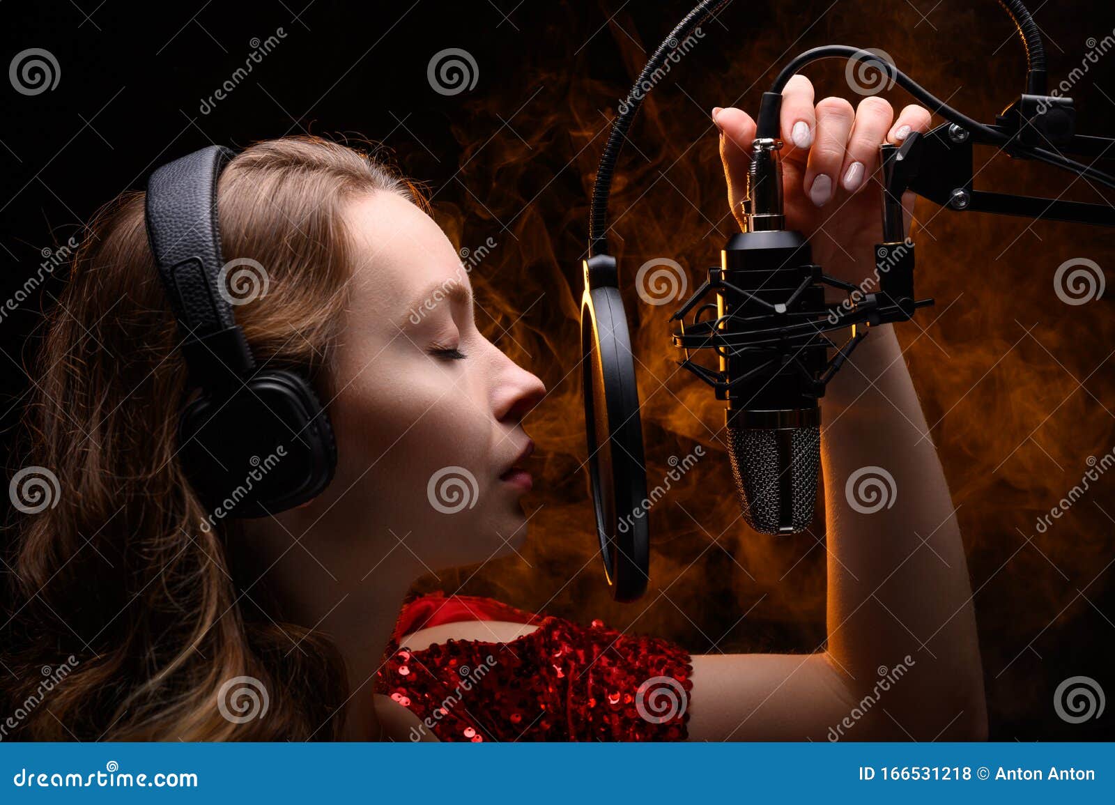 A Vocalist Sings into a Studio Microphone with Headphones on Her Head