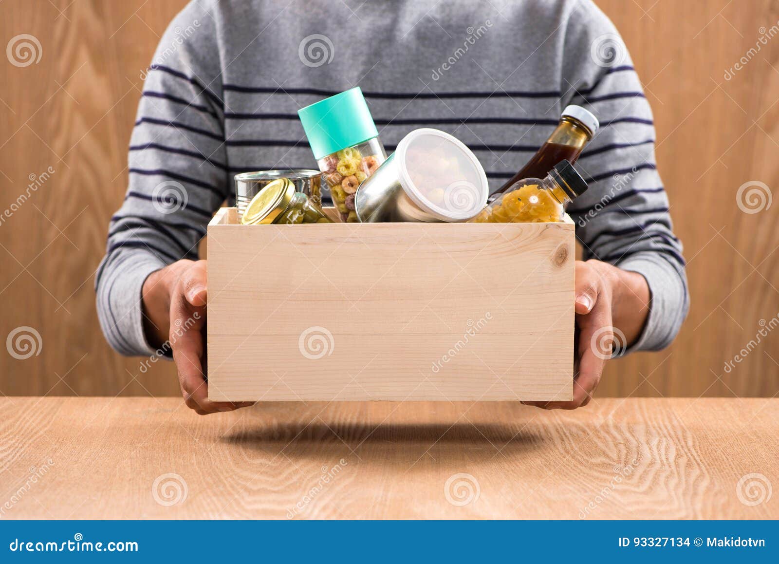 volunteer with donation box with foodstuffs on wooden background