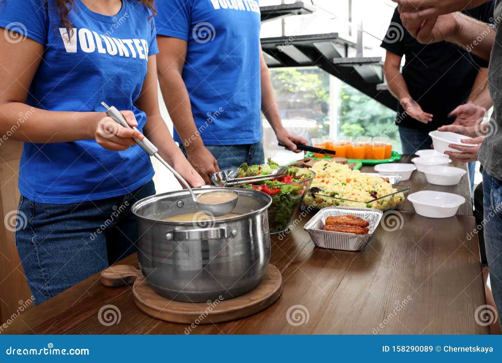 volunteers serving food to  people in charity centre, closeup