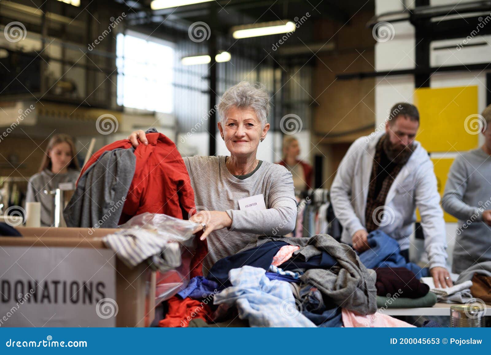 volunteers sorting out donated clothes in community charity donation center.