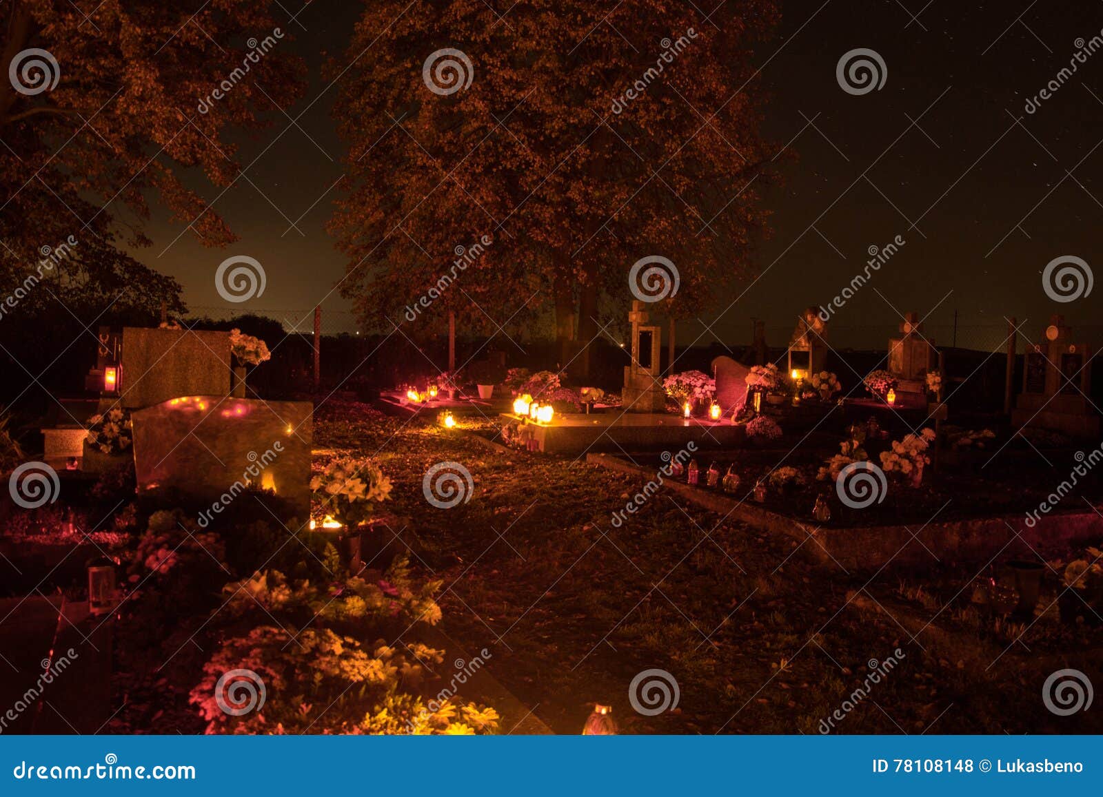 votive candles lantern burning on the graves in slovak cemetery at night time. all saints' day. solemnity of all saints