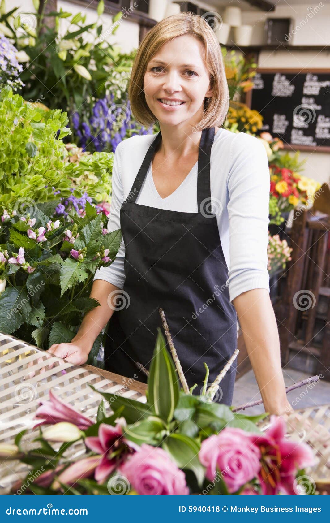 Vrouw die bij bloemwinkel het glimlachen werkt.