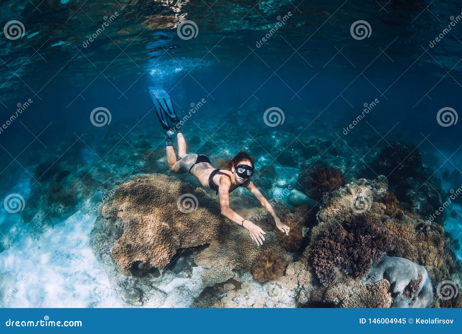 Vrouw freediver met vinnen en koralen Freediving onderwater in blauwe oceaan