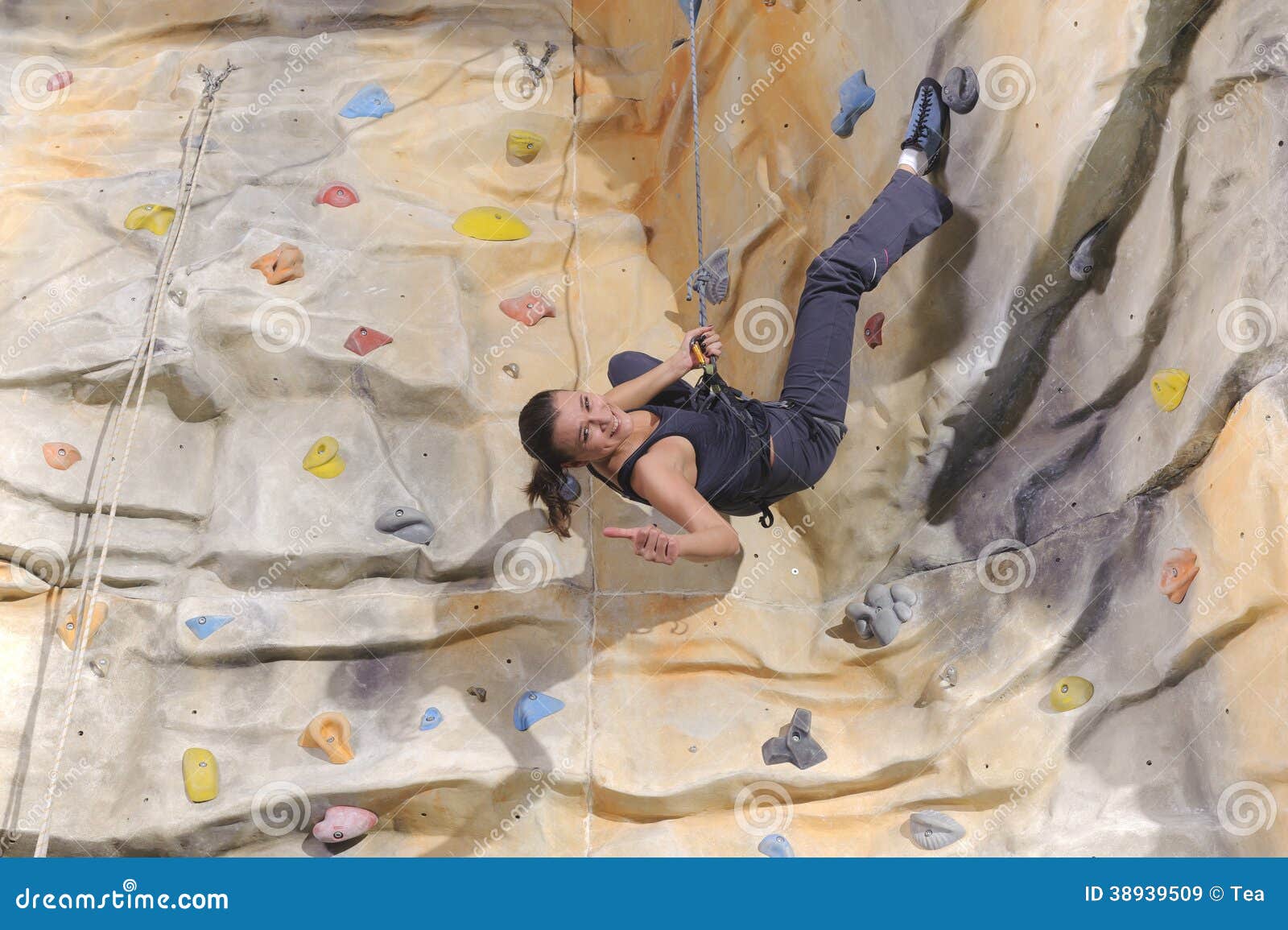 Actieve jonge vrouw op rotsmuur in sportcentrum