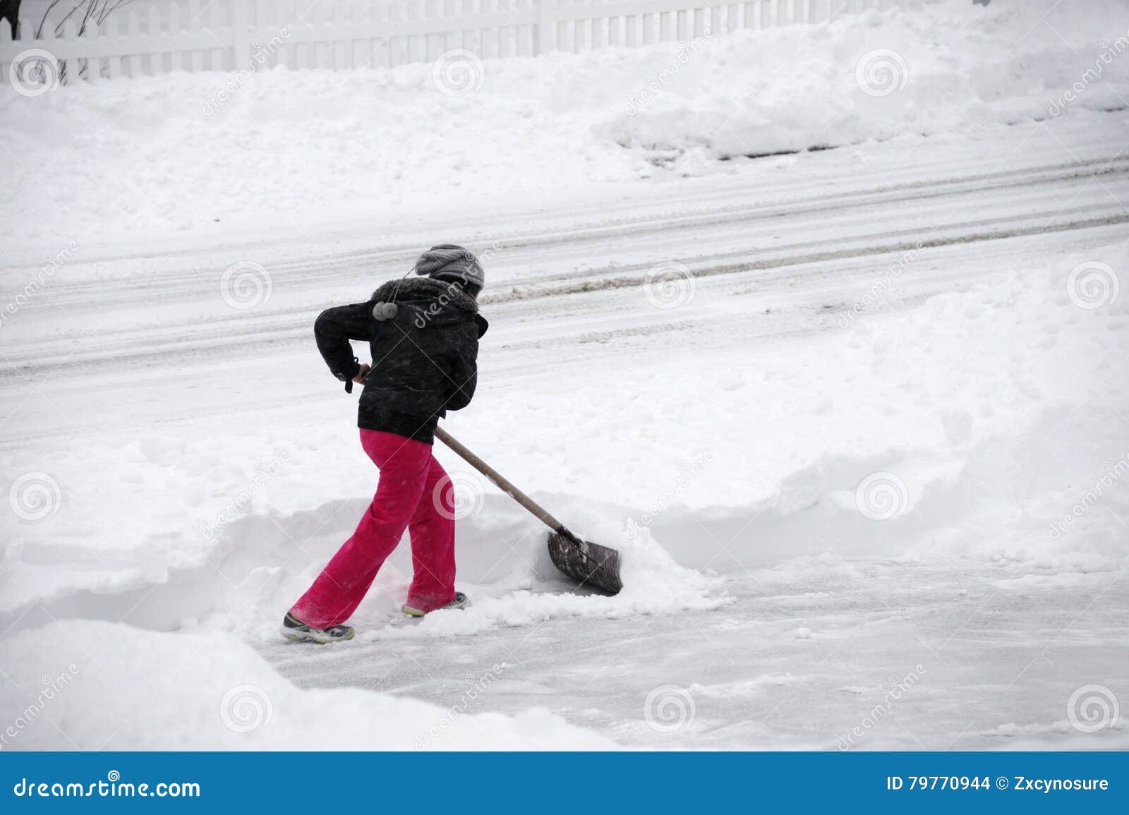 Vrouwen die sneeuw op de oprijlaan verwijderen door schop na blizzard