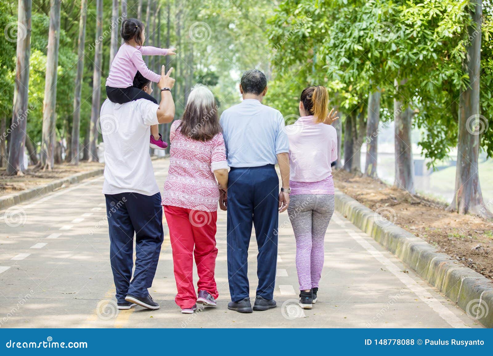 Vue arri?re de famille ?tendu marchant sur la route. Rear view of extended family enjoys leisure time while walking together on the road