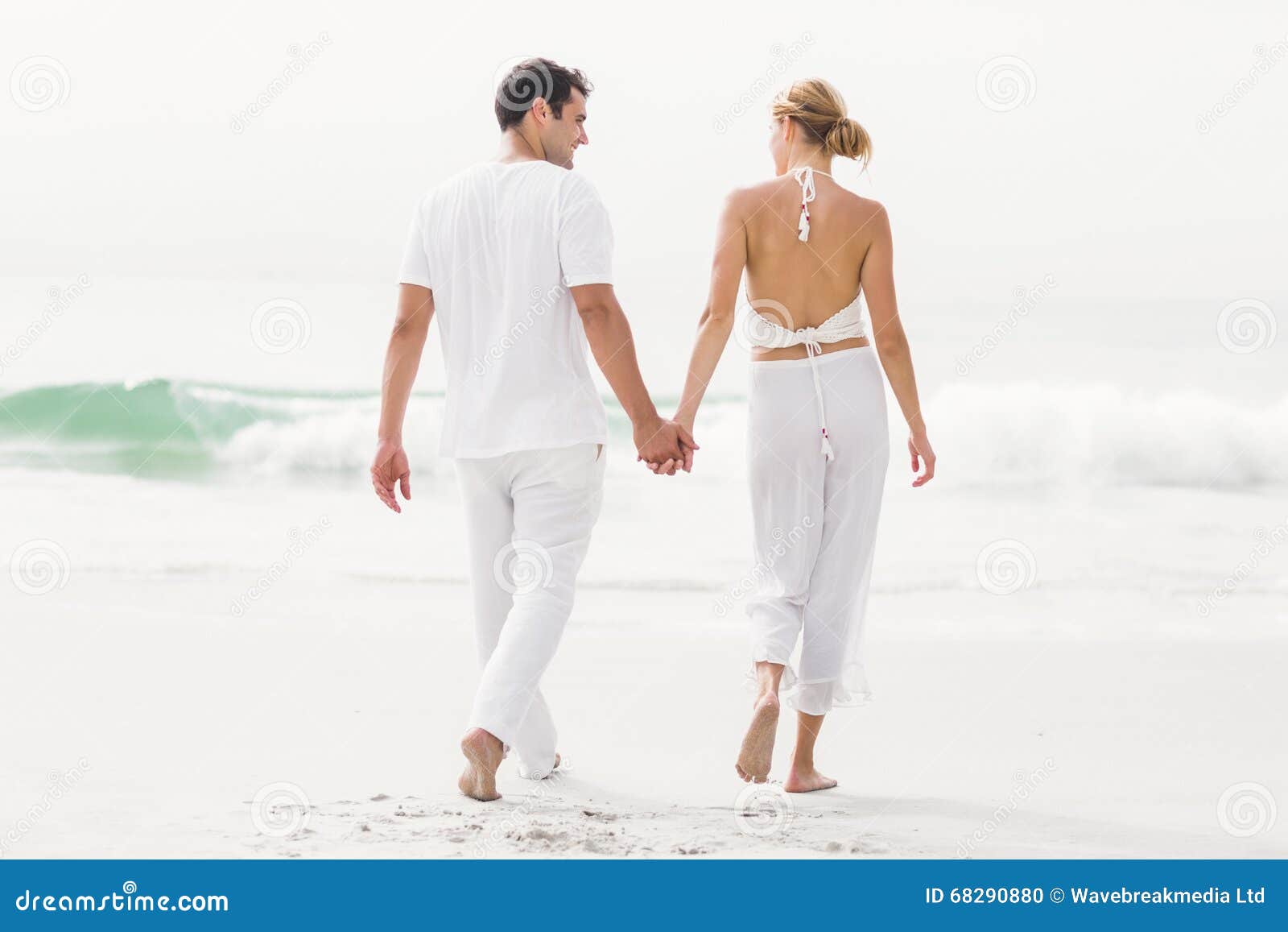 Vue arrière des couples marchant sur la plage un jour ensoleillé