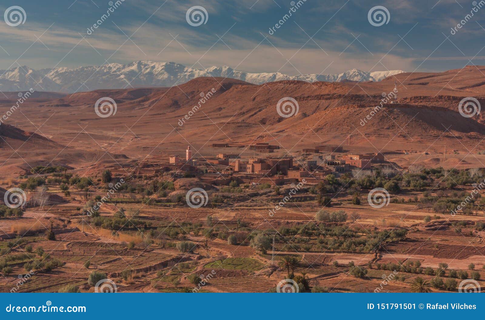 Vue d'un petit village. Ouarzazate, Maroc, Afrique - 15 janvier 2014 : Vue panoramique d'un petit village entouré par des cultures et la gamme de montagne de l'atlas neigeux de montagnes à l'arrière-plan, Sahara, Maroc