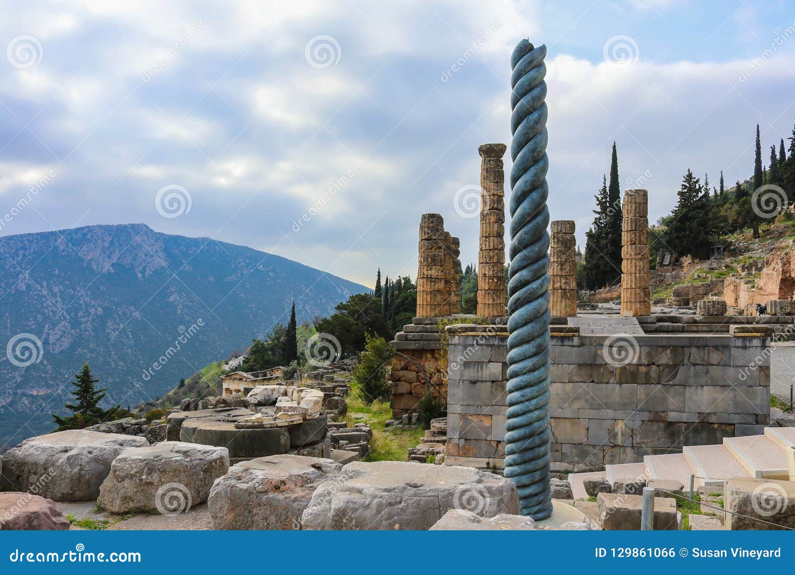 Vue de site de flanc de montagne de Delphi Greece antique avec la colonne tordue devant le temple d'Apollo avec un trésor en bas d'une colline et d'une montagne différente dans la distance à travers la vallée