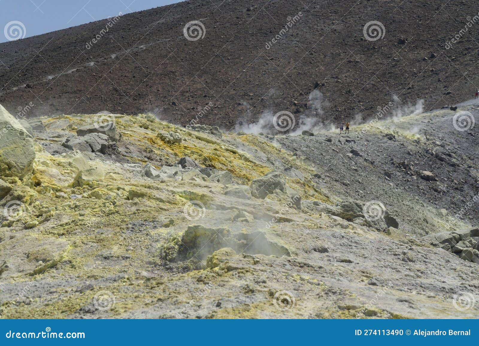vulcano trekking with fumaroles and a couple of touris walking on the ground path with big mountain