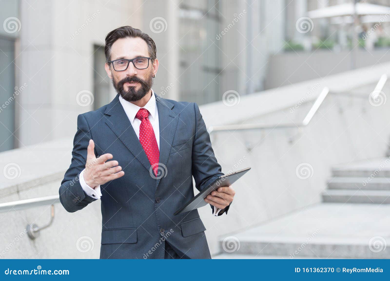 waist up of affluent businessman having a talk with you while holding a tablet in hand