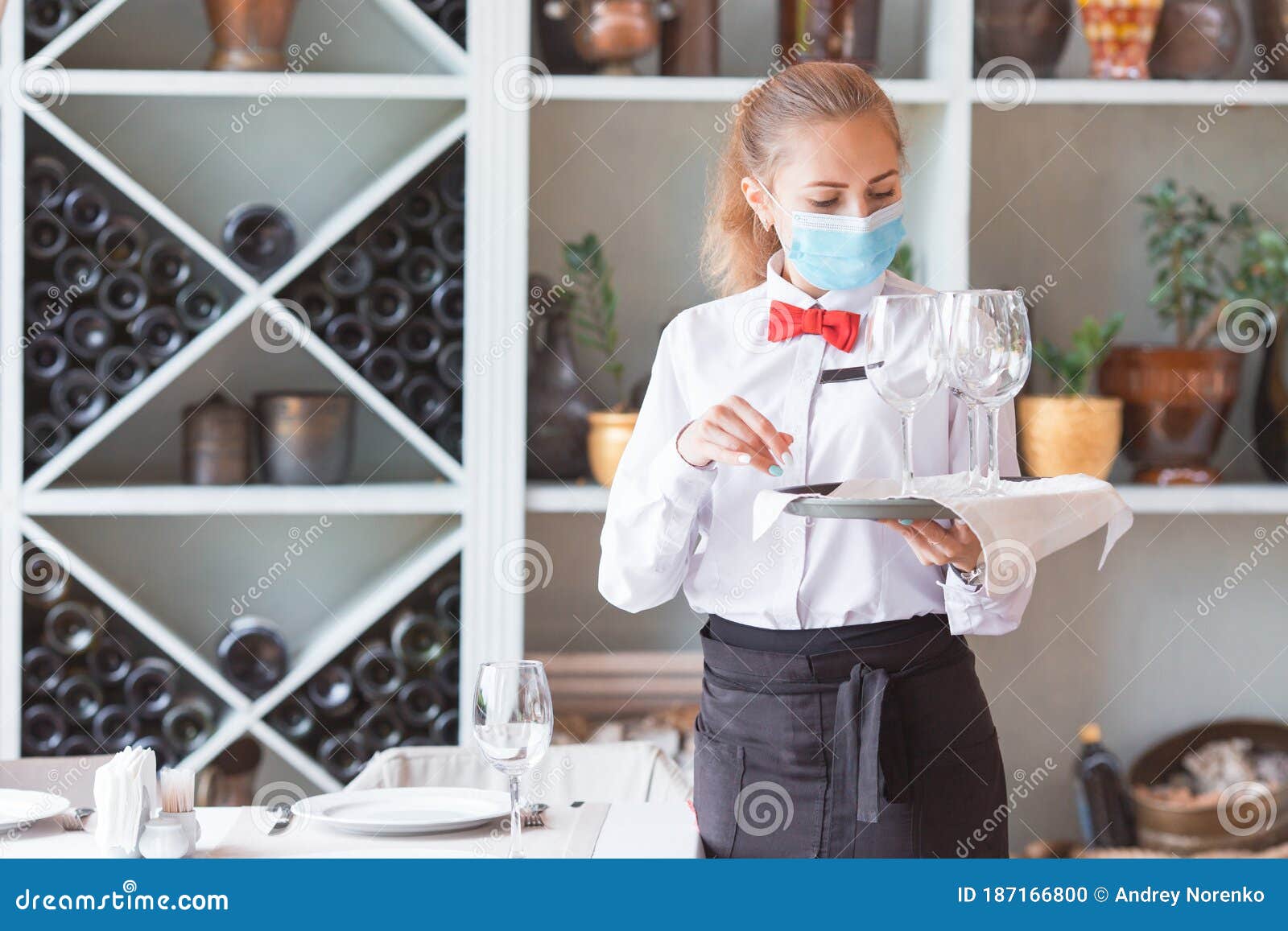 the waiter serves a table in a cafe in a protective mask