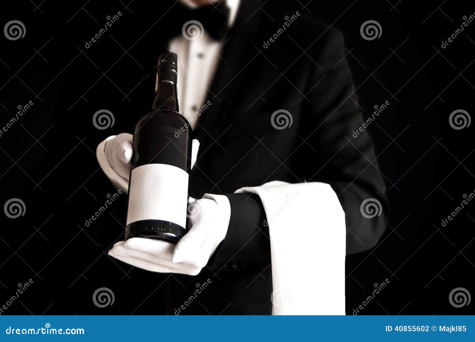 waiter in tuxedo holding a bottle of red wine