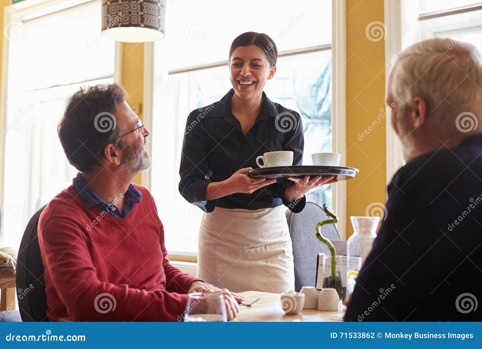 waitress bringing coffees to a male couple at a restaurant