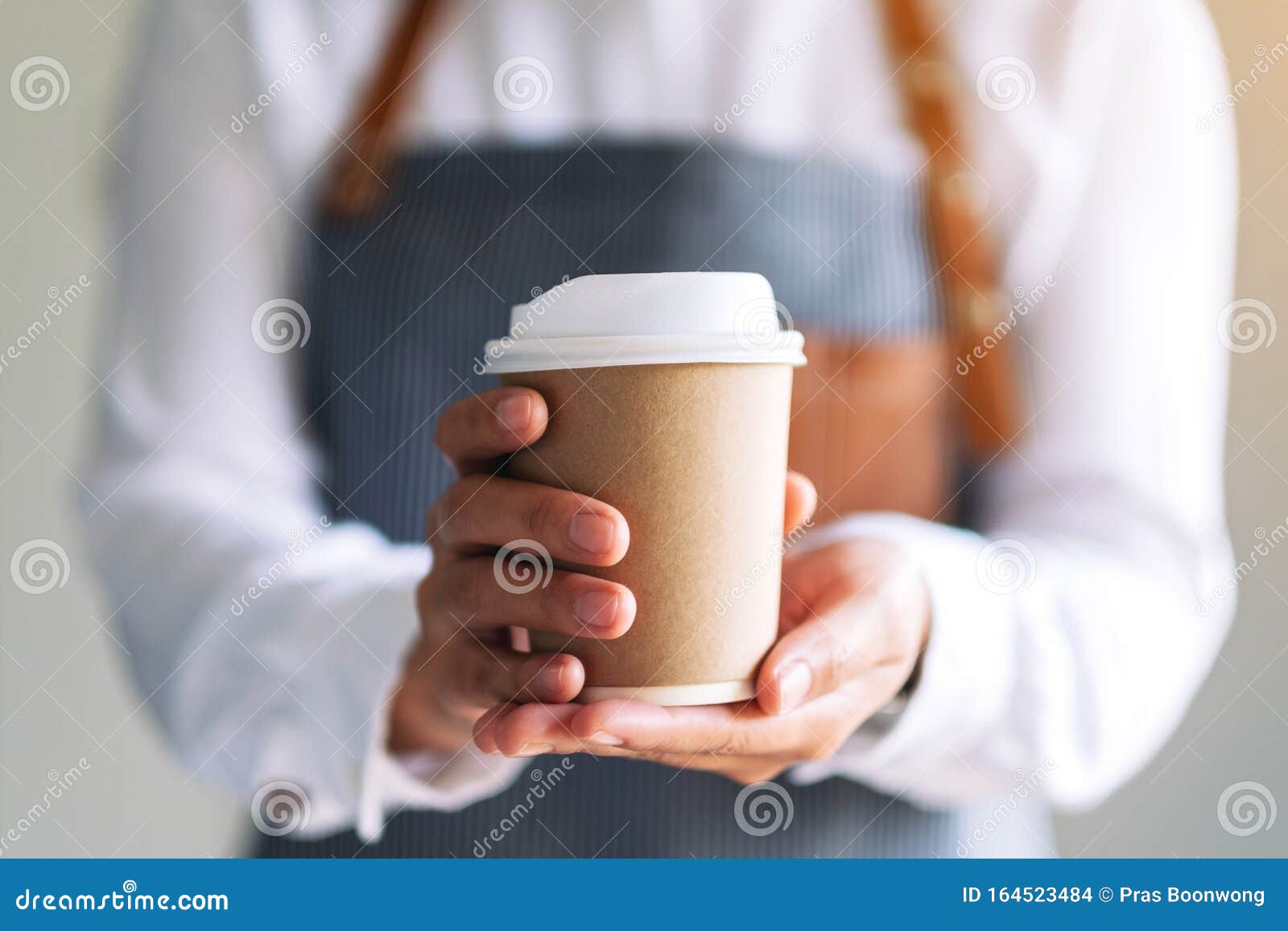 a waitress holding and serving a paper cup of hot coffee