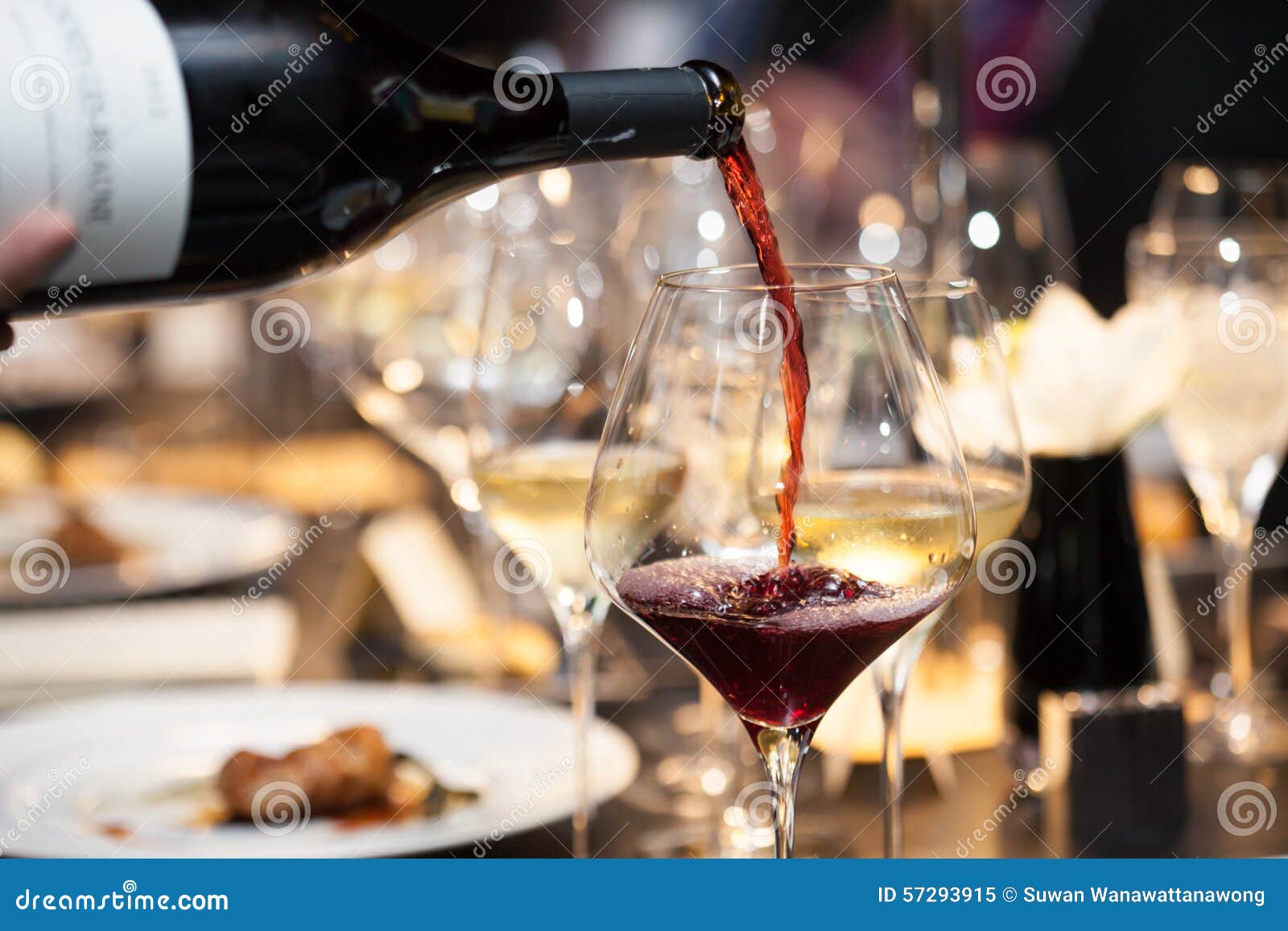 Waitress Pour Red Wine in the Glass on the Table in Restaurant Stock