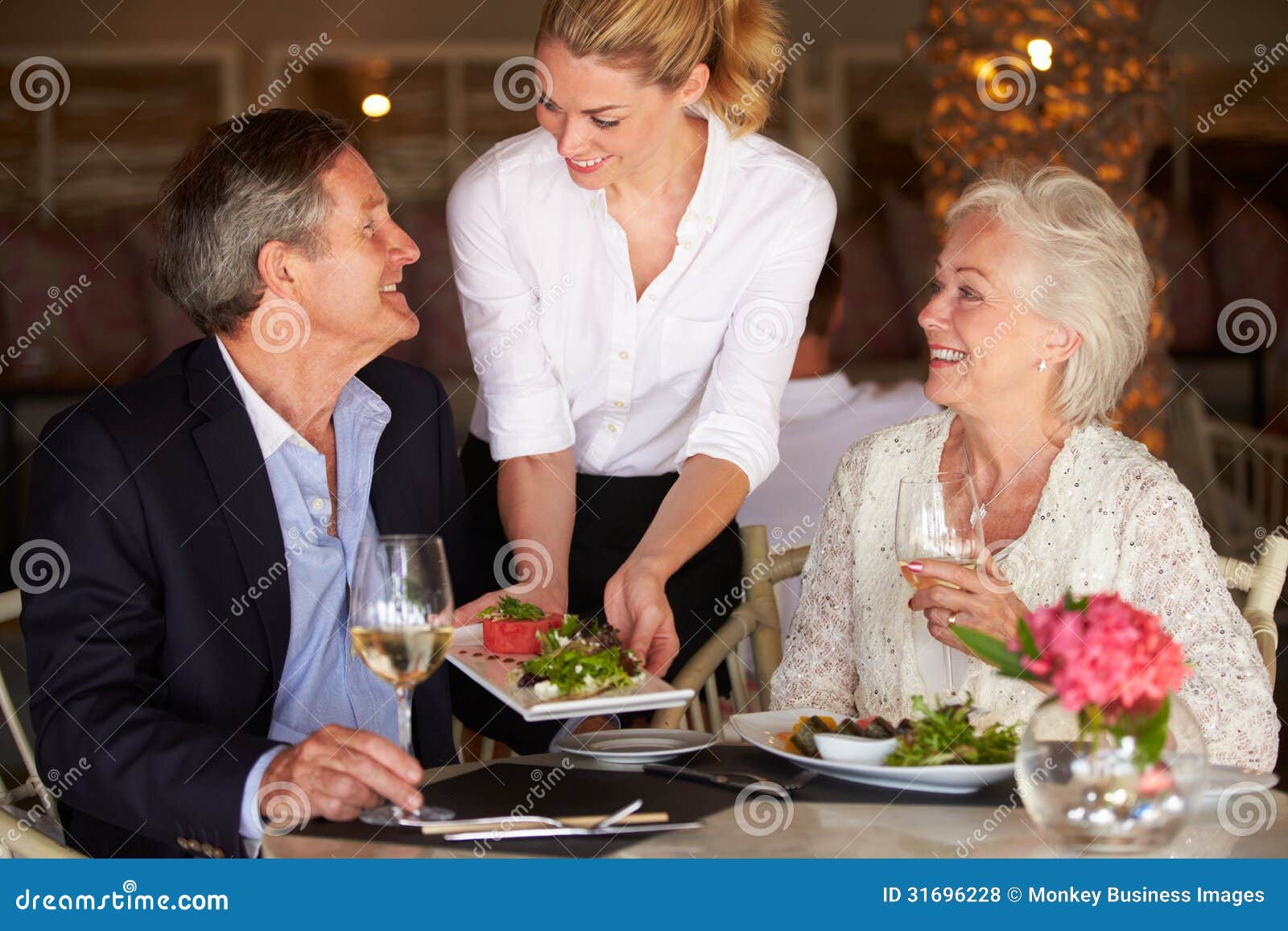 waitress serving food to senior couple in restaurant