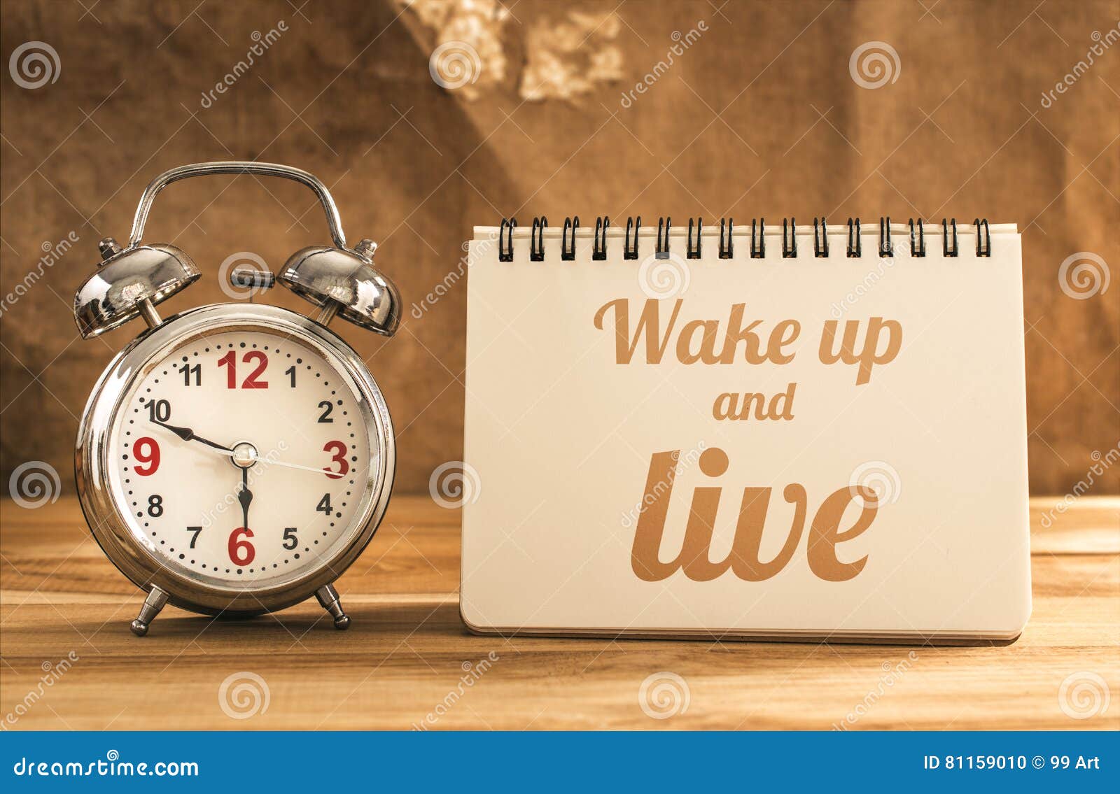 wake up and live text on notebook with alarm clock on wood table