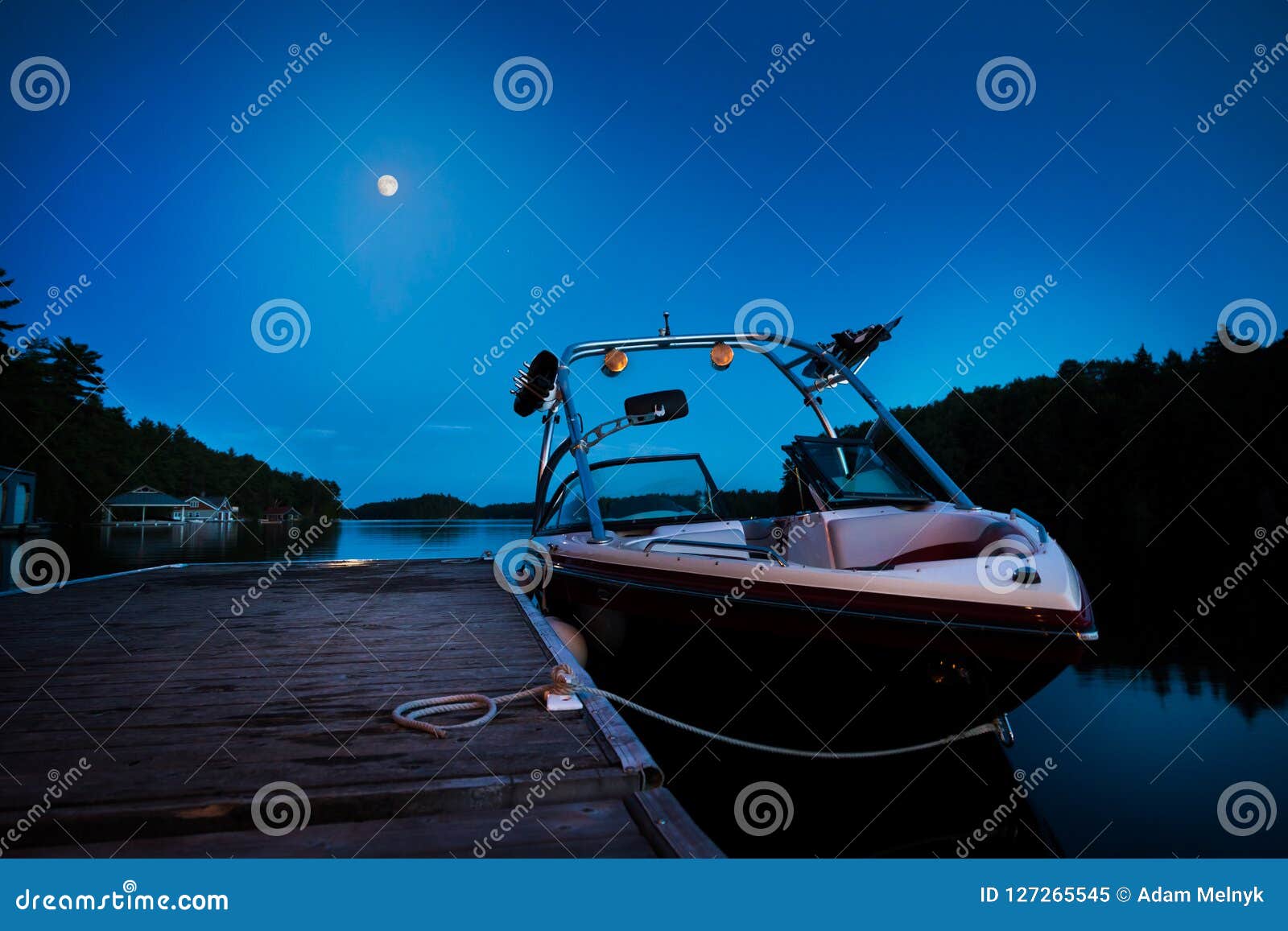 A Wakeboard Boat Docked on Lake Joseph in the Evening with the Moon in