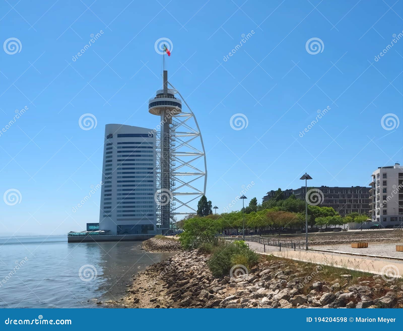 walking the footpath passeio do tejo along tagus river in lisbon at the expo park - with the tower