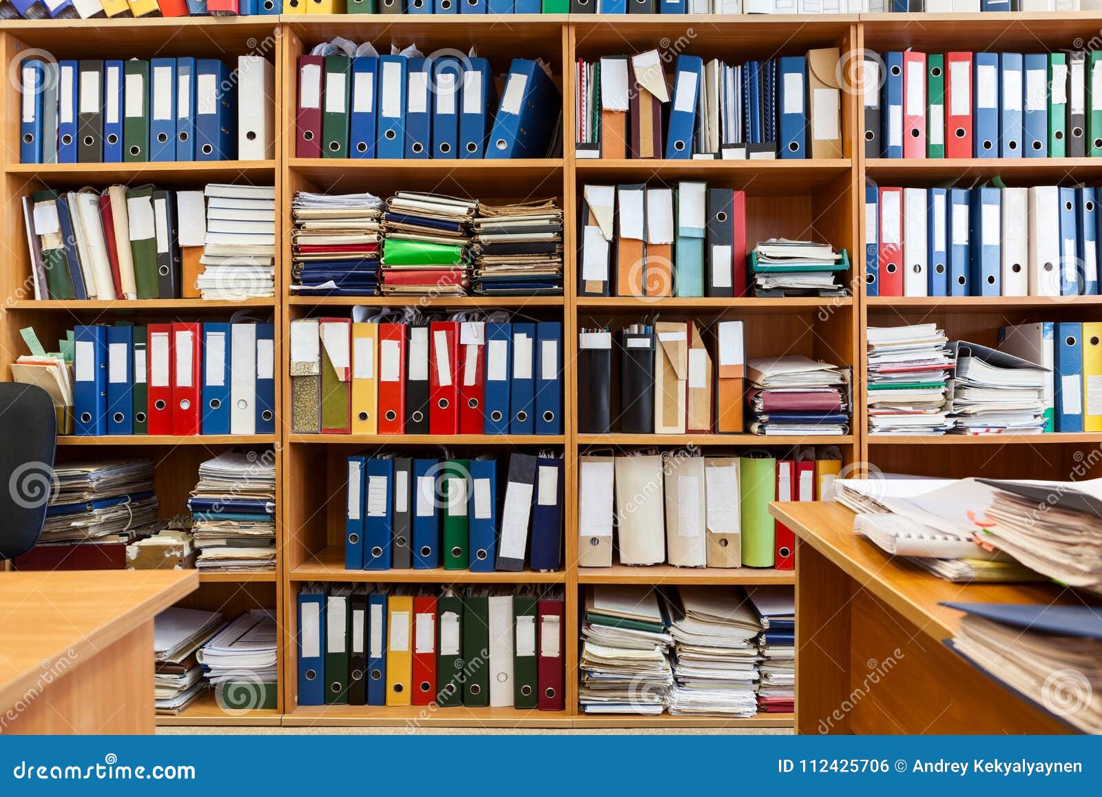 wall from shelves with colourful file binders, an office room with papers and documents