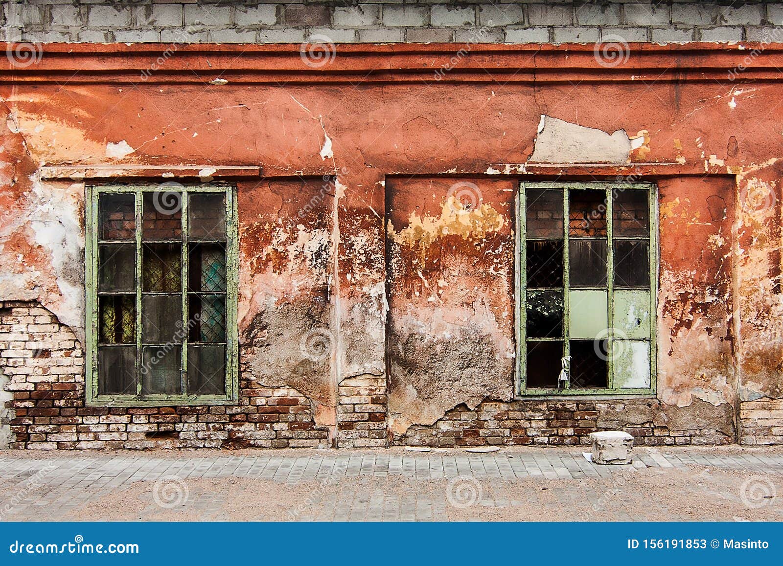 wall with two broken windows of abandoned building in mariupol