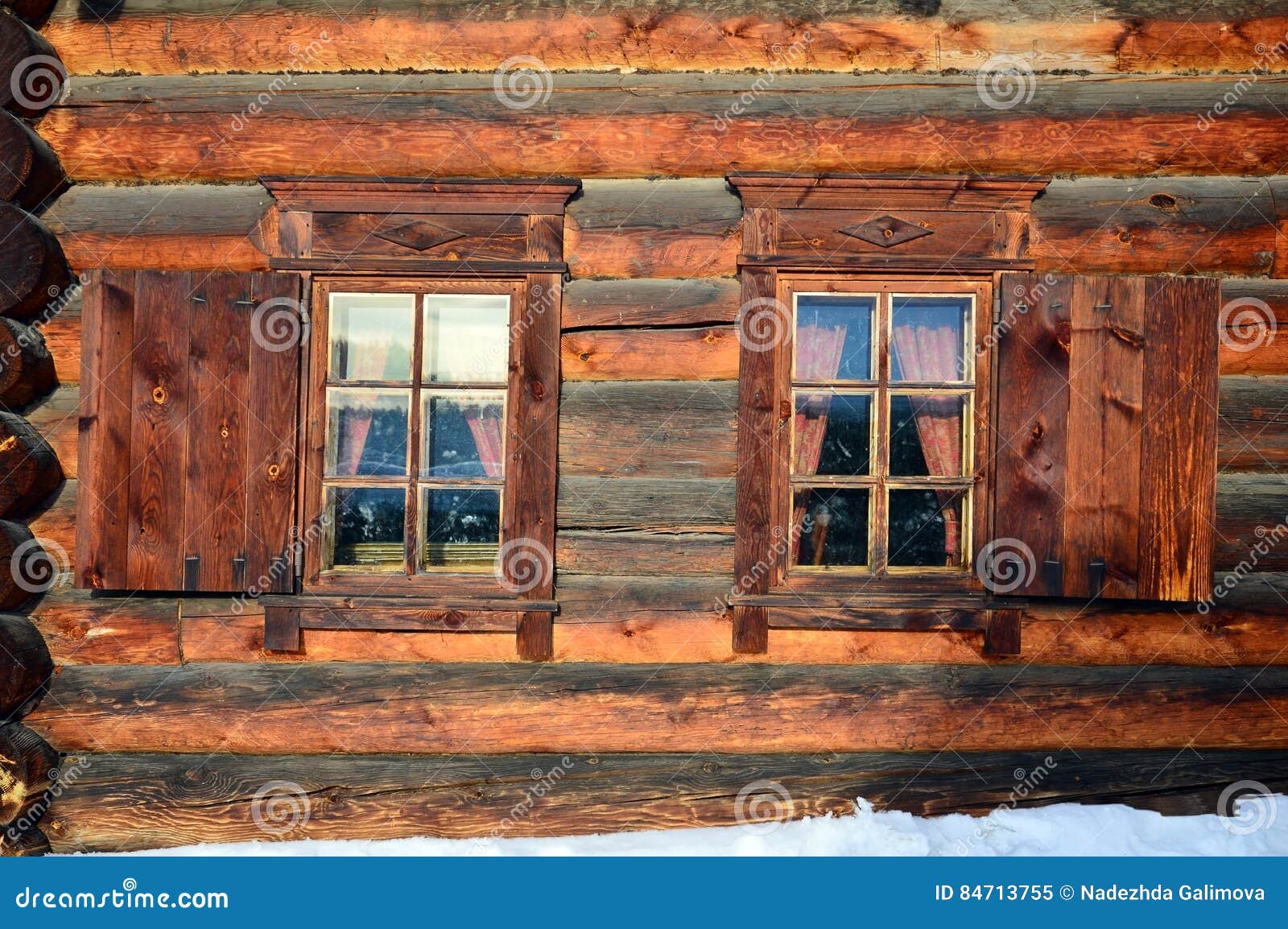 wall with two windows of wooden houses from round logs. winter. the museum of wooden architecture under the open sky. russia, sibe