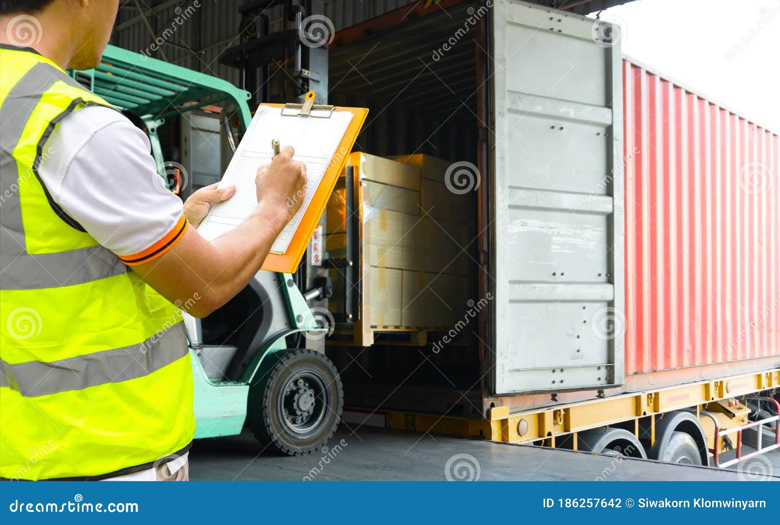 warehouse worker holding clipboards control forklift loading shipment goods into container truck.