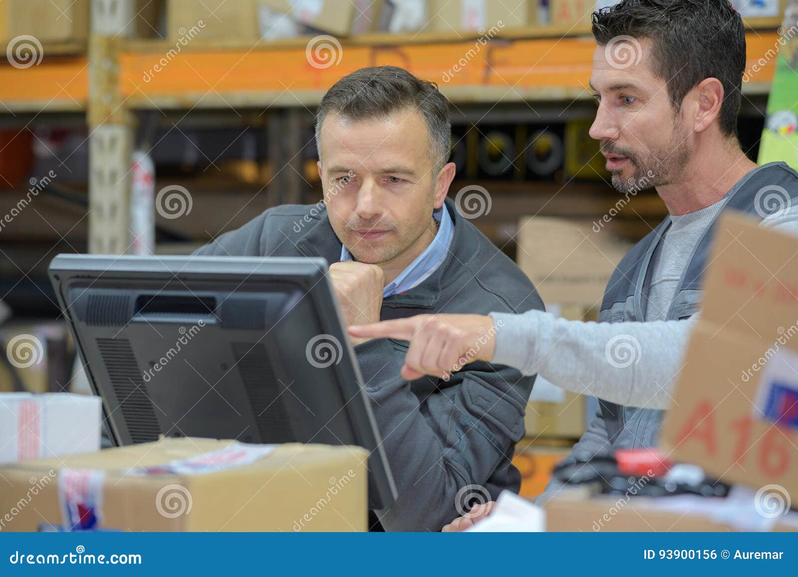 Warehouse Worker and Manager Using Computer in Warehouse Stock Photo