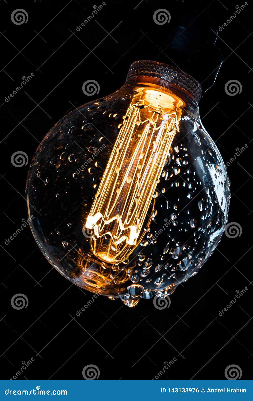 Warm Colored and Glowing Bulb with Water Drops on a Dark Background