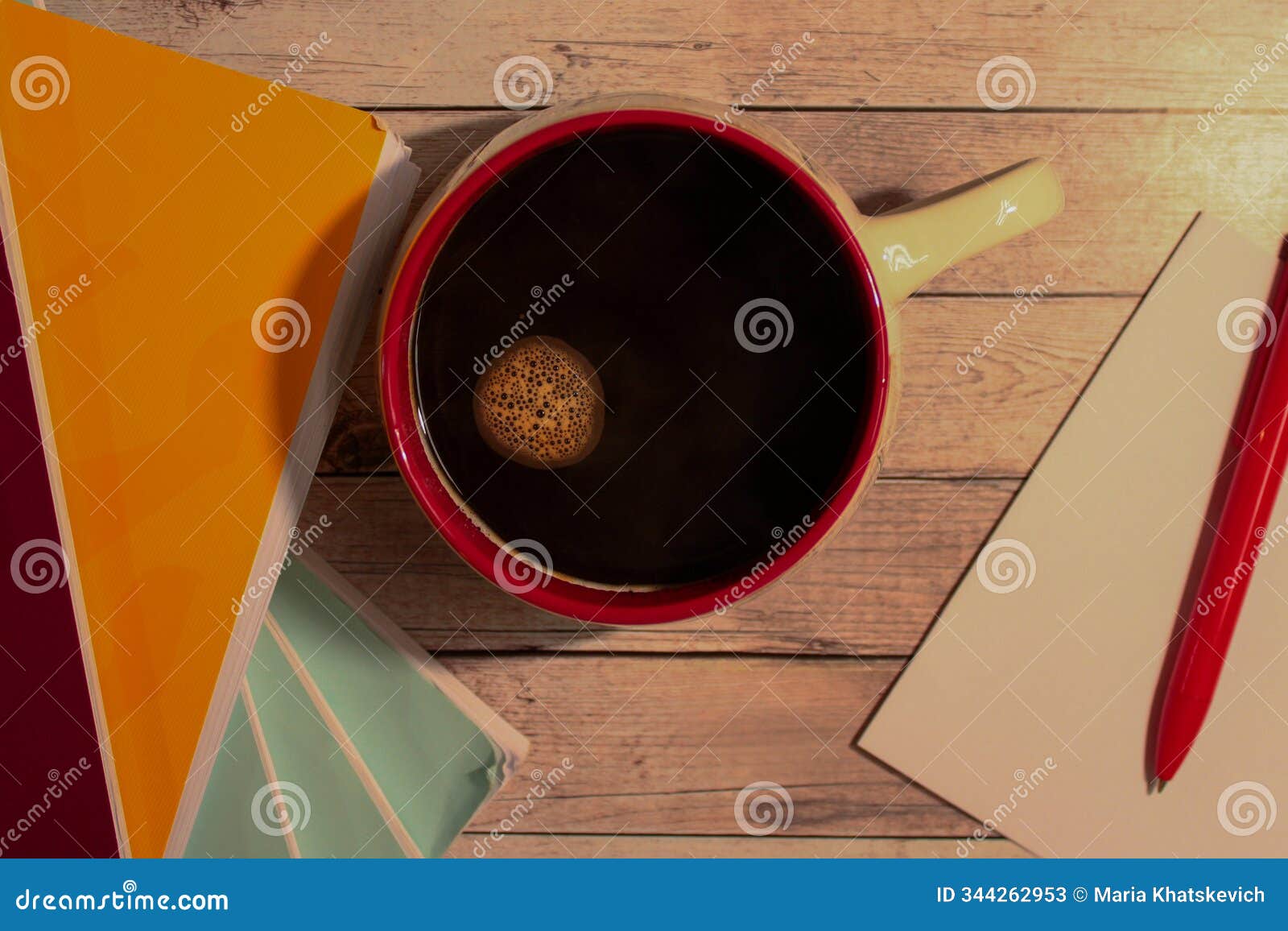 a warm, cozy scene with a top-down view of a red-rimmed coffee mug filled with black coffee