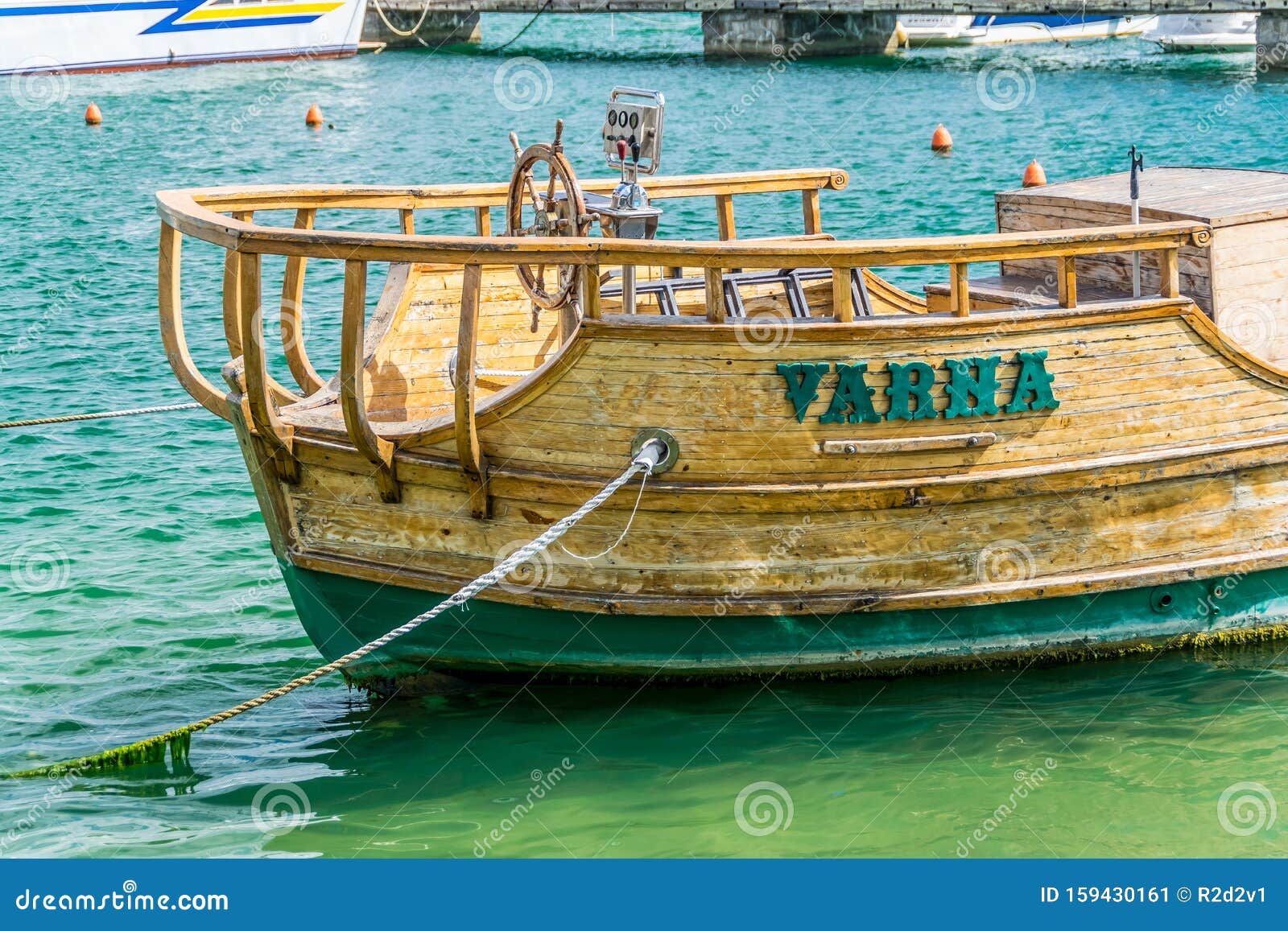 Warna — stary drewniany pirat. Bliski widok starego, zacofanego, drewnianego pirata statku Warna z otwartą sterówką na molo ośrodka Golden Sands w Bułgarii Zielone algi na powierzchni wody i liny