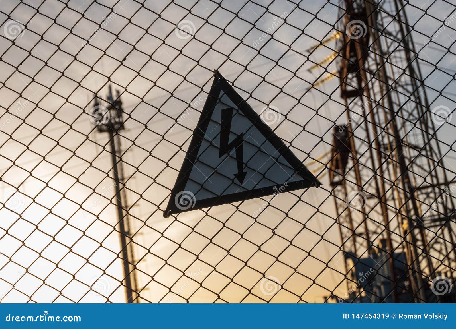 Warning Triangular Sign with a Lightning Image on the Net Fence