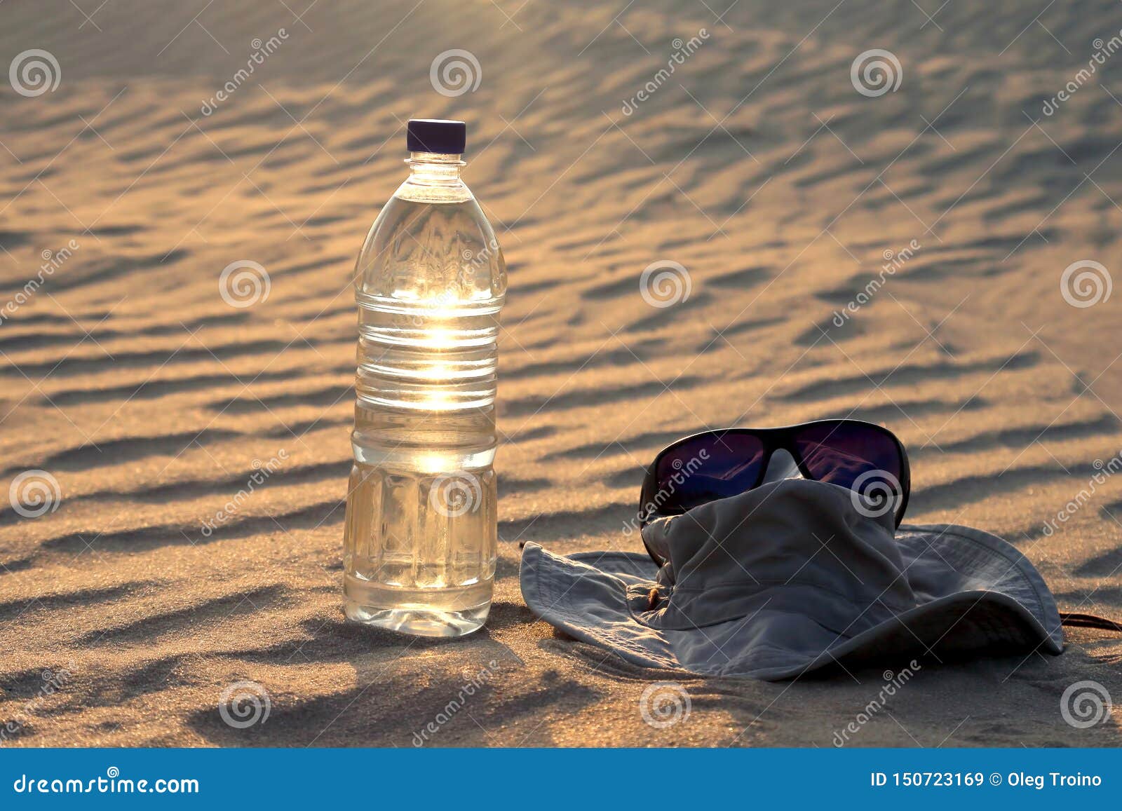 Water Bottle, Hat and Sunglasses Lying on the Sand in the Desert Stock