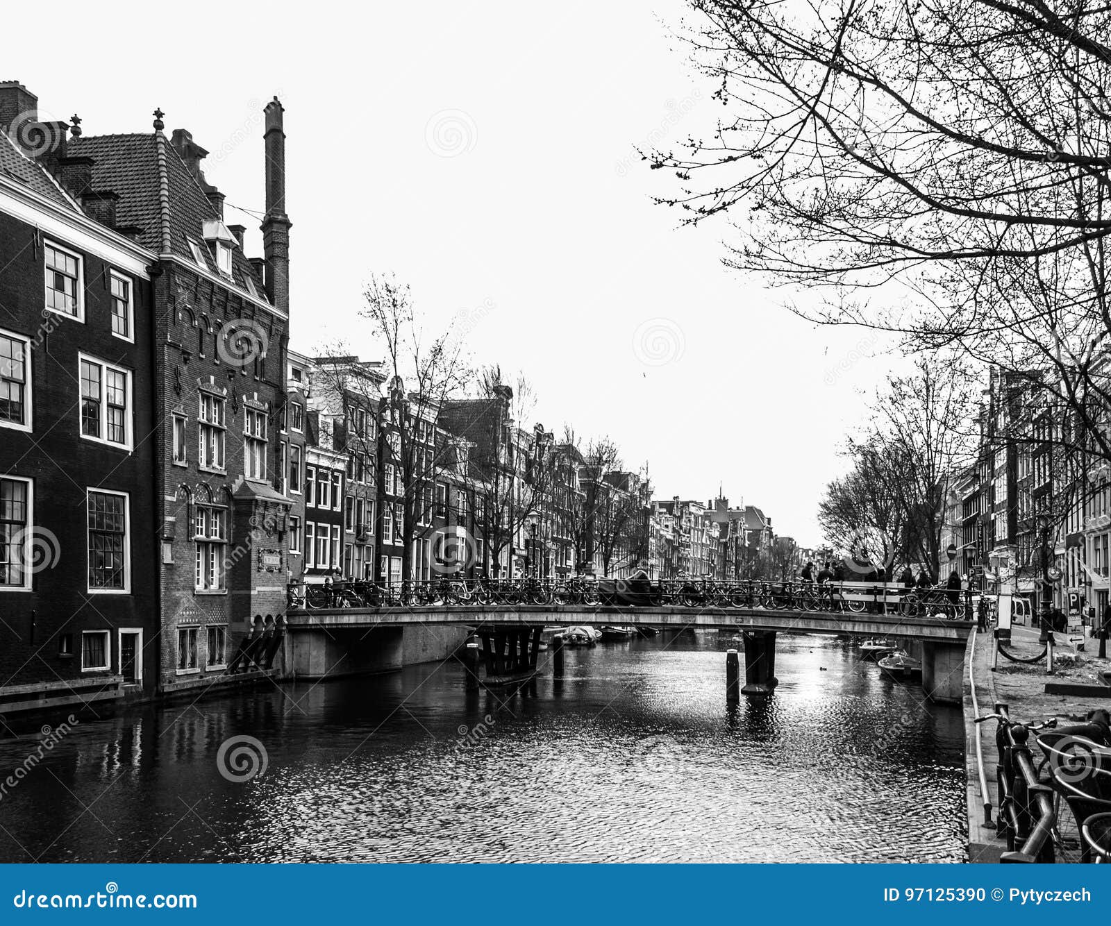 water canal, aka gracht, and narrow houses along it in amsterdam city centre, netherlands, black and white image