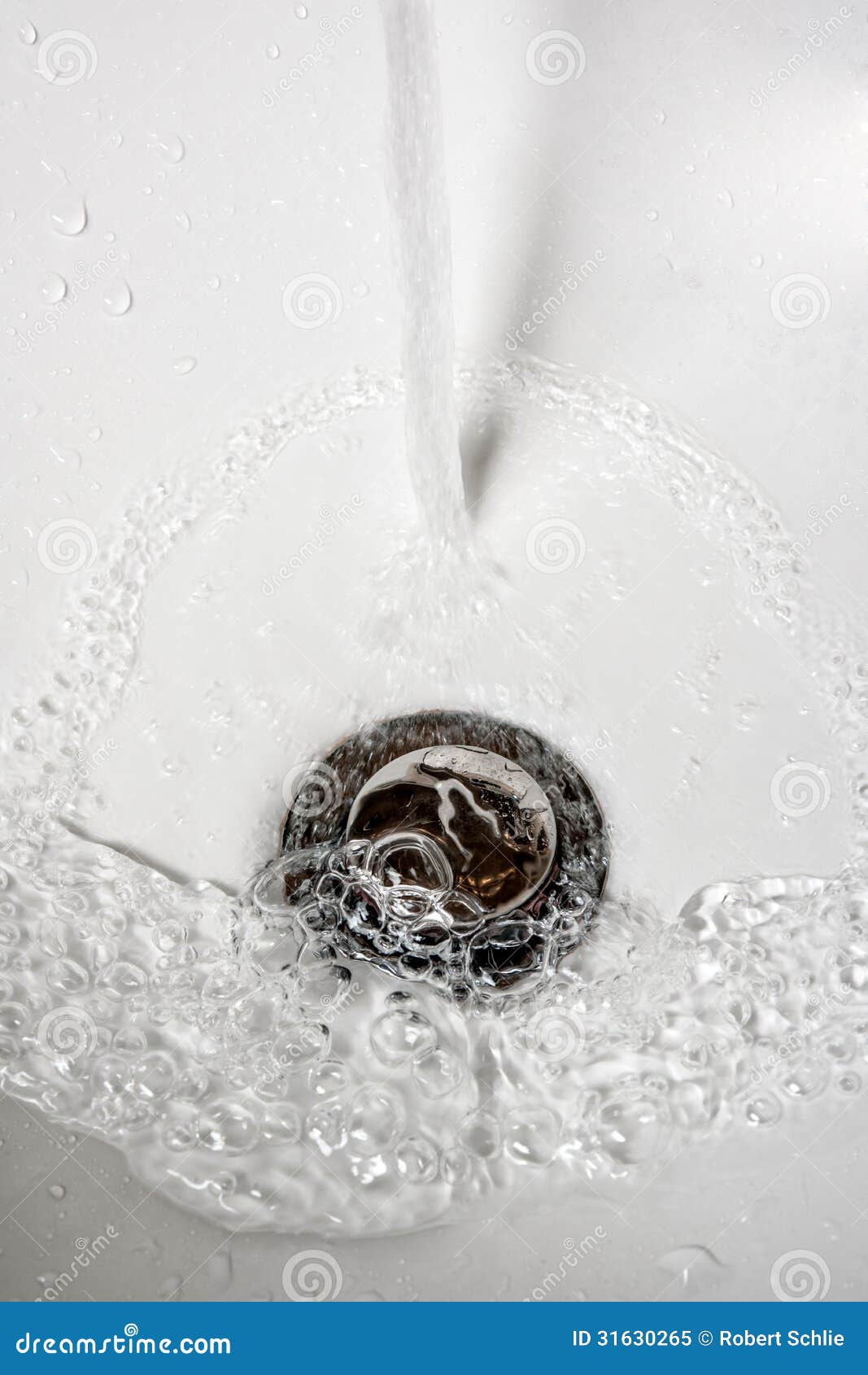 Water Down The Drain. Steady stream of water into a porcelain sink and down the drain.