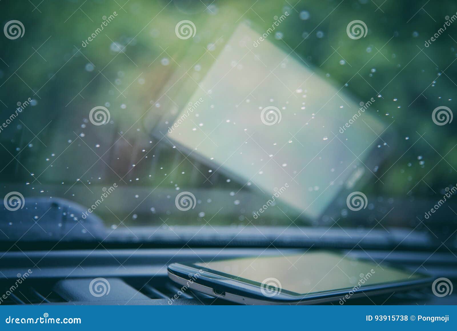 Water drops on car windshield with smartphone. Water drops steam of rain on car windshield window glass after the rain with smartphone on car console