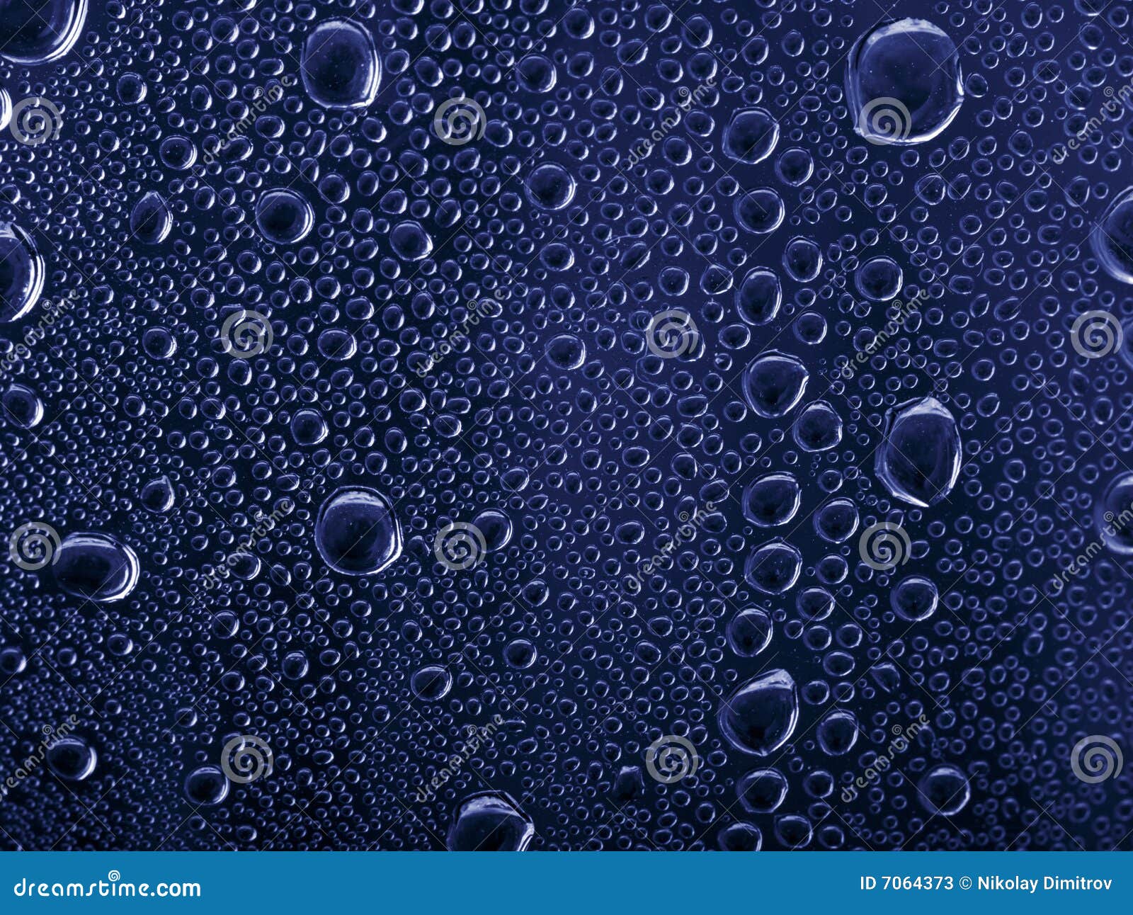 Water drops on a dark blue glass. Bright water drops on blue glass