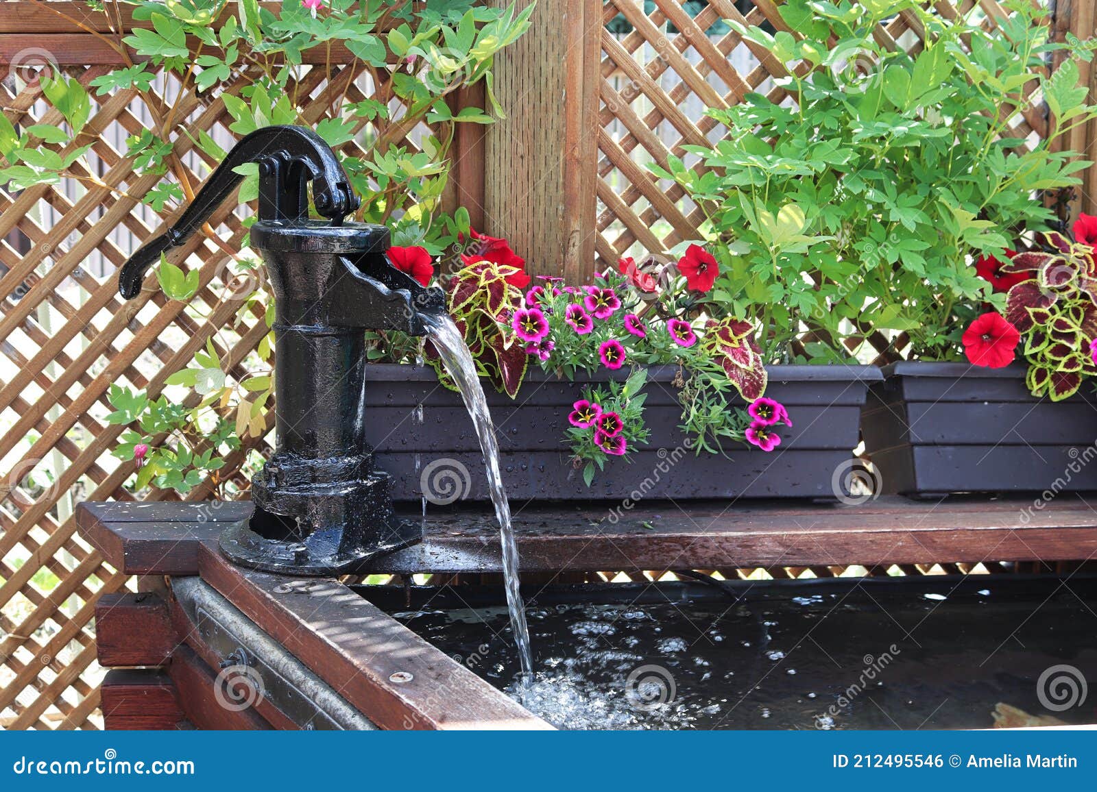 a water fountain infront of a lattice with annuals