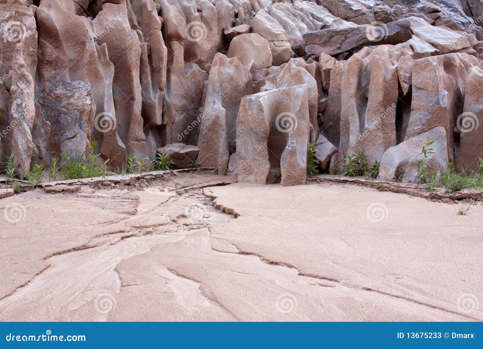 water-sculpted rocks and sand in desert canyon