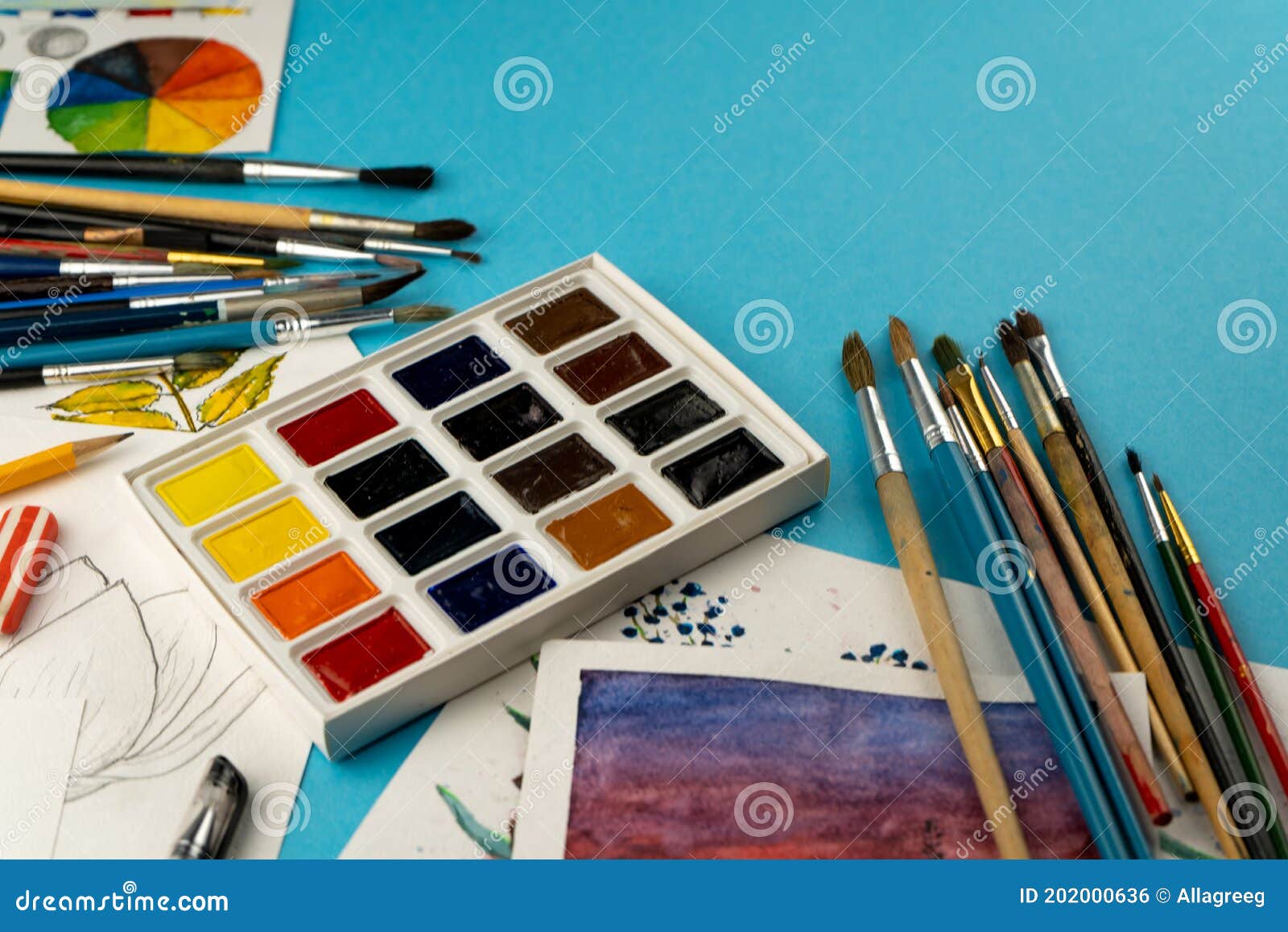 watercolor paints and brushes. artist`s workplace and desk. color palette. drawing blue background. place for your text. art