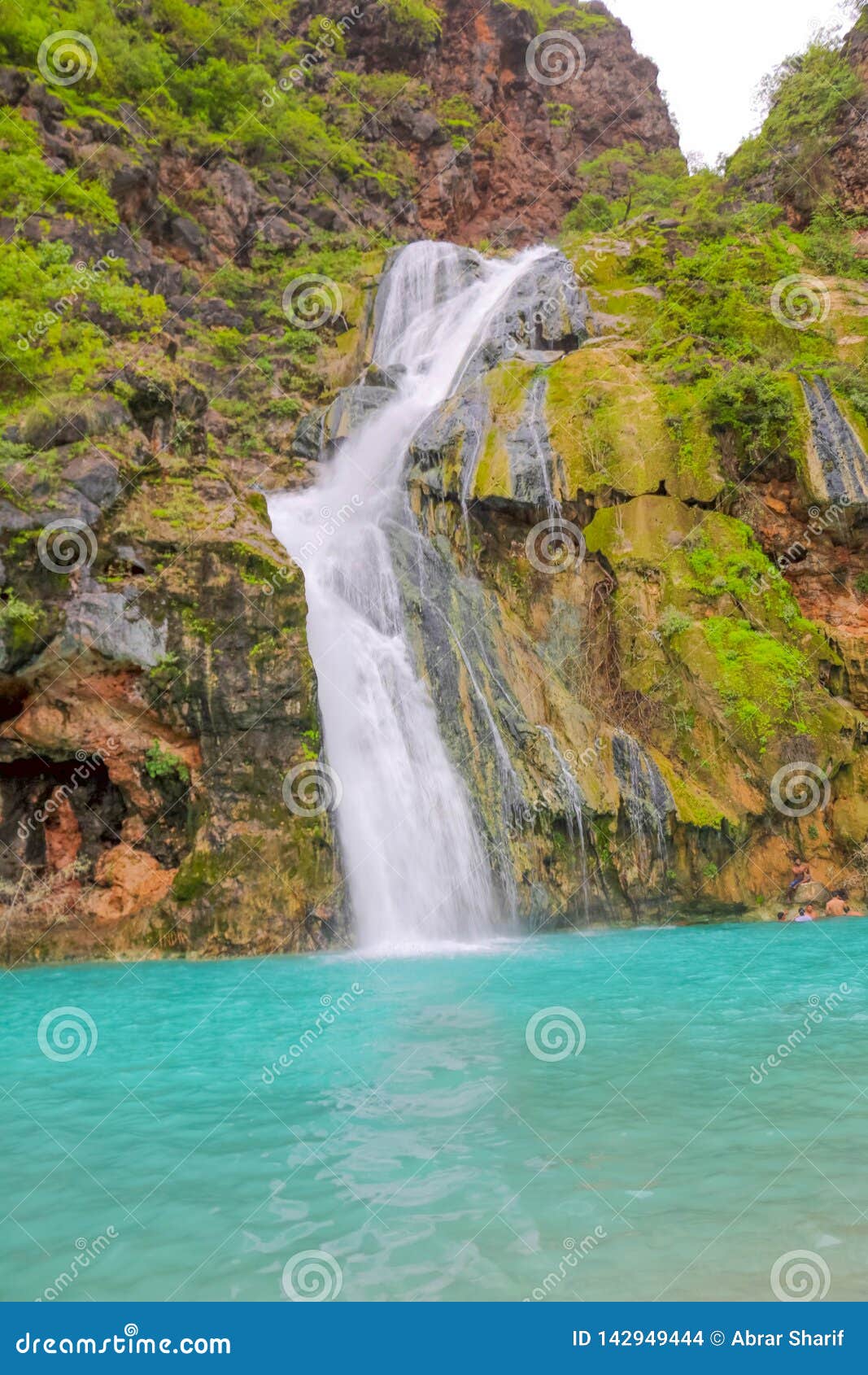 waterfall in ayn khor and lush green landscape, trees and foggy mountains at tourist resort, salalah, oman