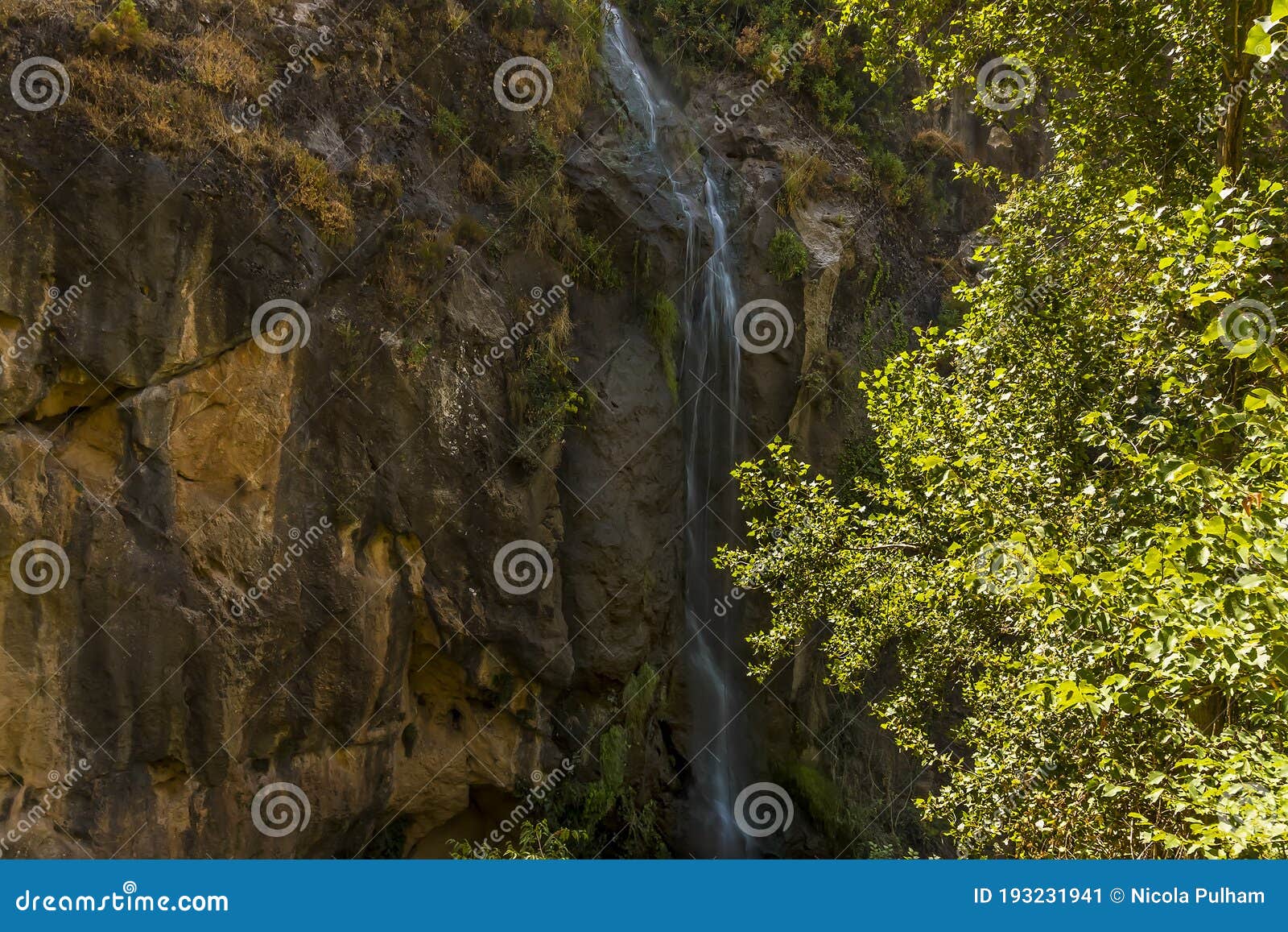 a waterfall cascades down the side of a mountain in the sierra nevada mountains outside monachil, spain