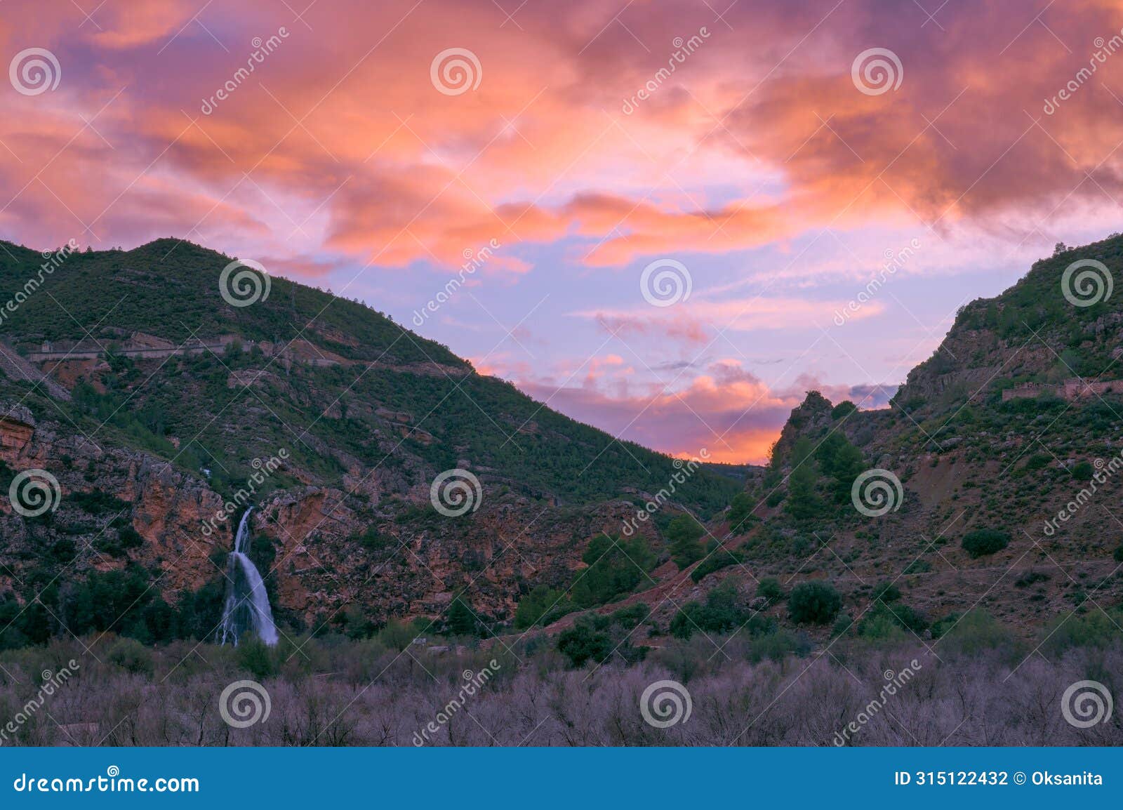 waterfall cascading against a breathtaking sunset backdrop.