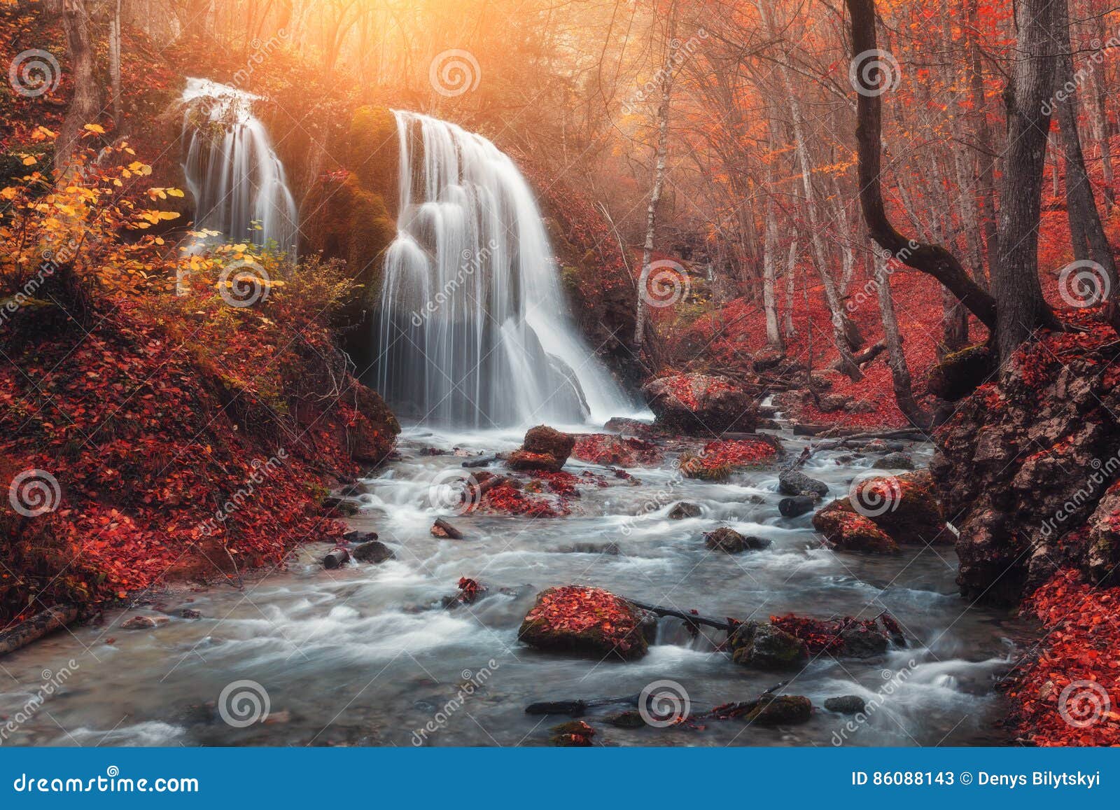 waterfall at mountain river in autumn forest at sunset