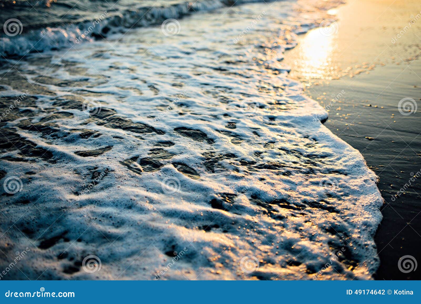 wave of the ocean sea on the sand beach at the sunset light.