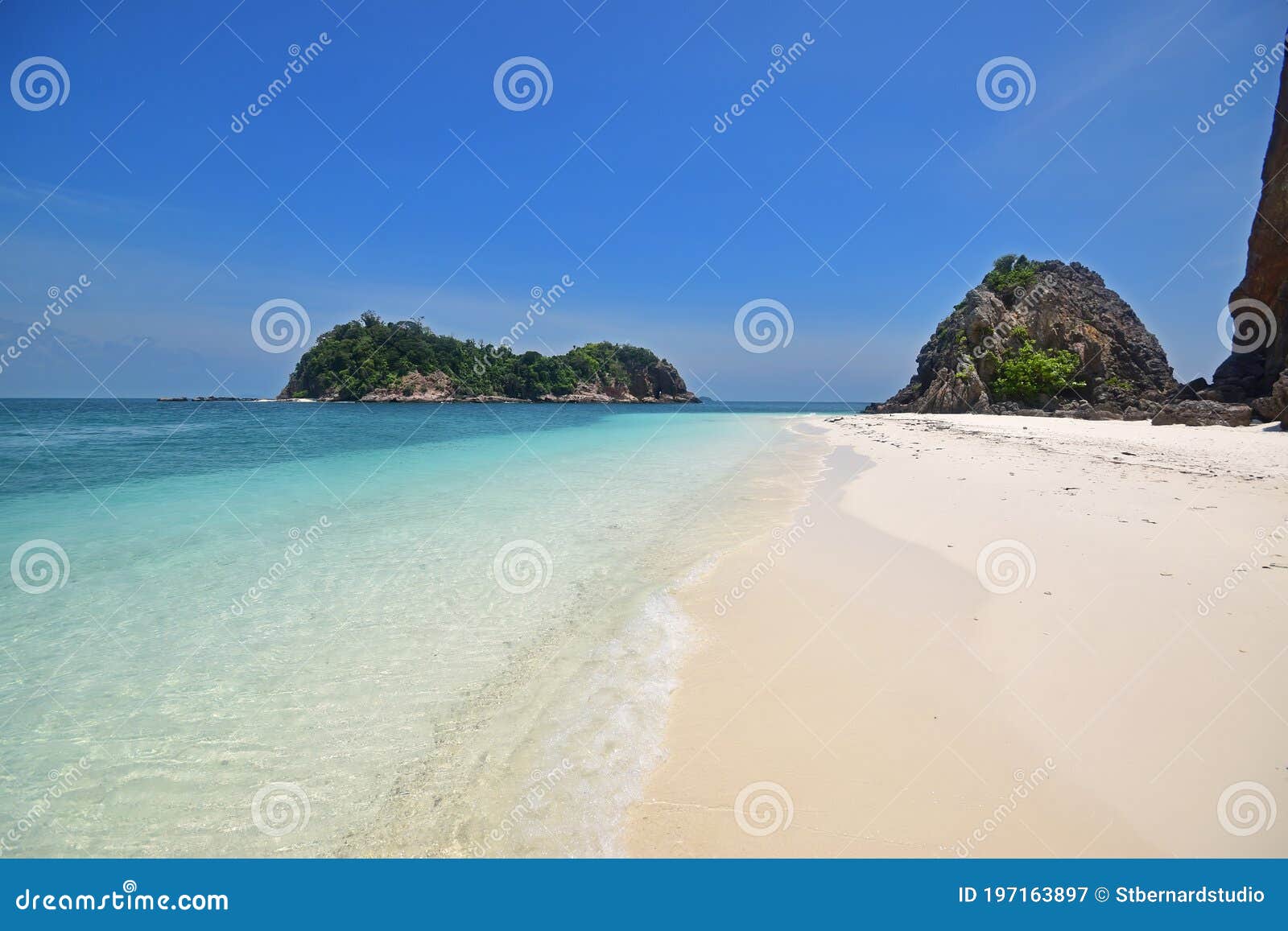 wave on white fine sandy sand & shallow blue water with speed boat & cloudless sky at pulau lima besar island, johor, malaysia